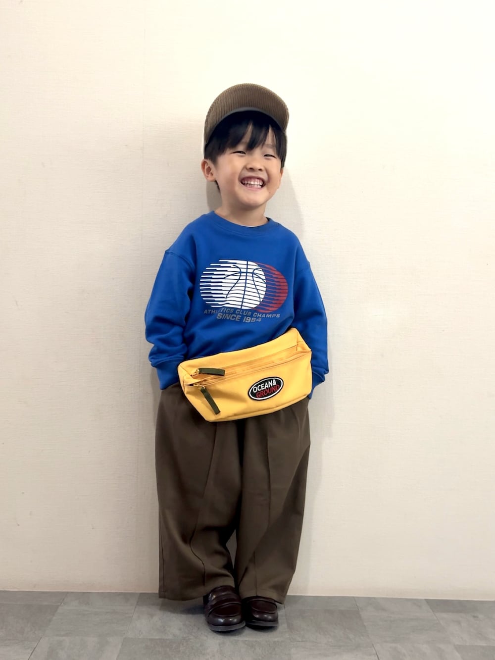 ブラウン系のスラックス、ブラウン系のローファー、ブルー系のスウェットを着用したキッズの秋コーディネートの3枚目の写真