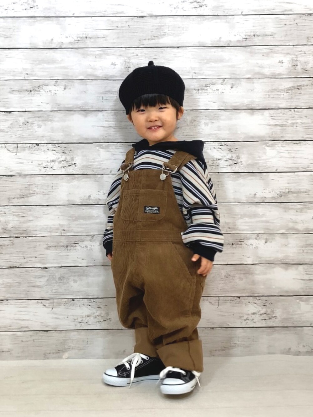 ブラック系のパーカー、ブラウン系のサロペット/オーバーオール、ブラック系のスニーカーを着用したキッズの冬コーディネートの2枚目の写真