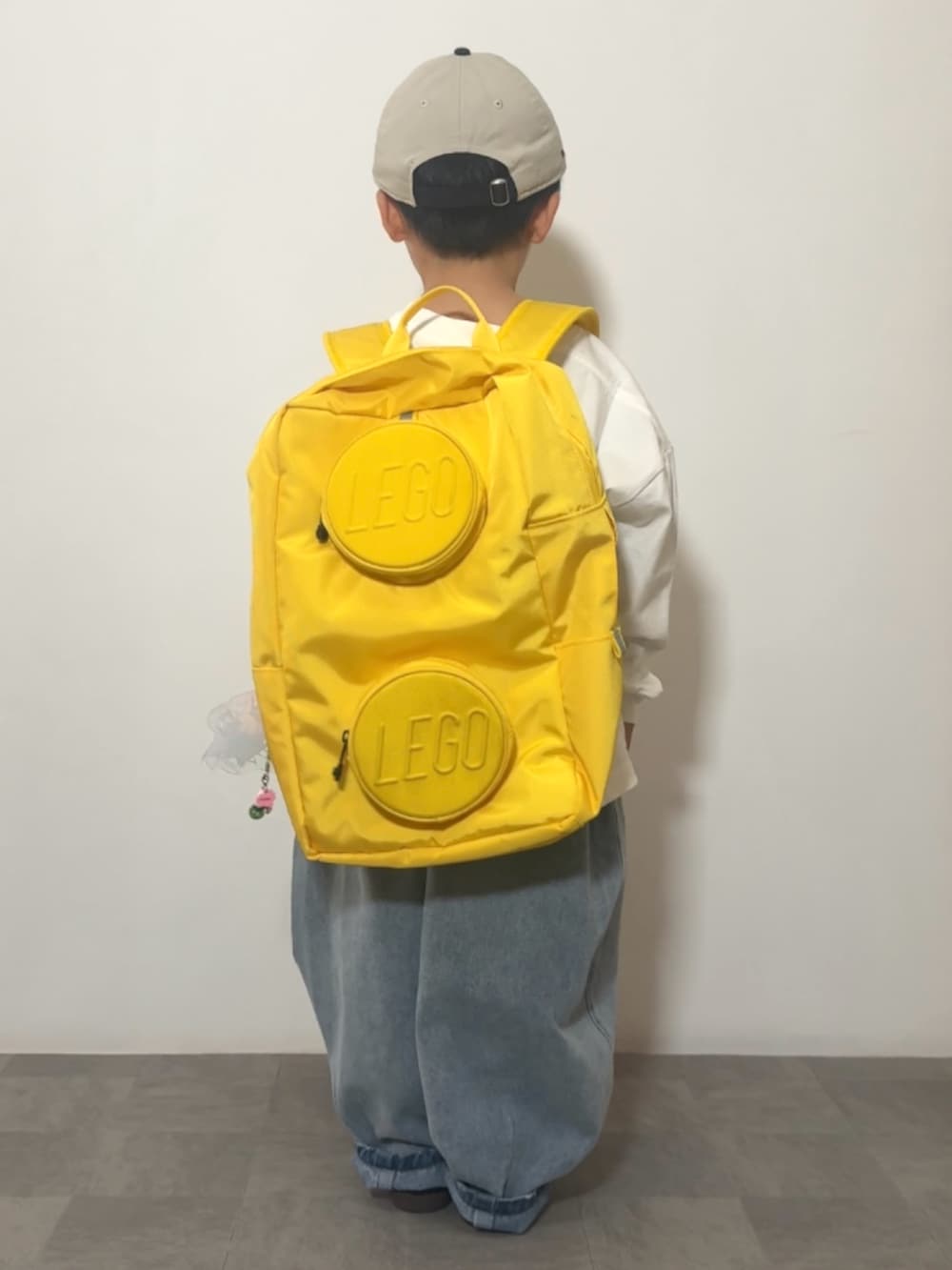 イエロー系のバックパック/リュック、ブラック系のスニーカー、ホワイト系のTシャツ/カットソーを着用したキッズの春コーディネートの5枚目の写真