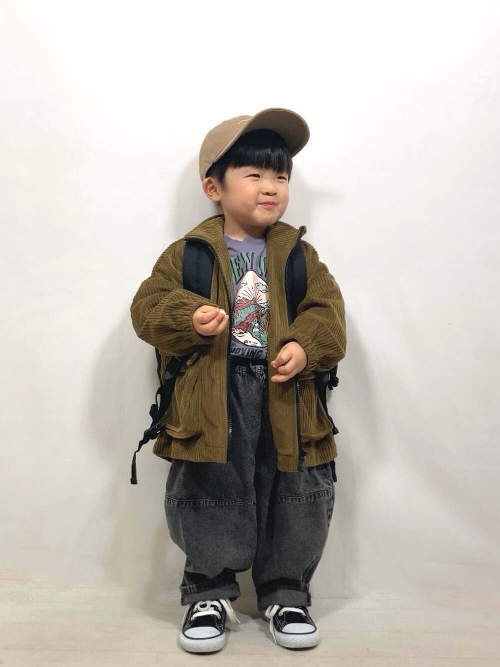 グリーン系のブルゾン、パープル系のTシャツ/カットソー、ブラック系のデニムパンツを着用したキッズの冬コーディネートの2枚目の写真