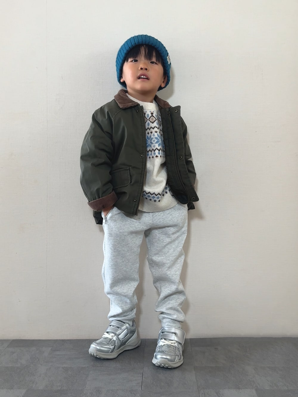 シルバー系のスニーカー、ホワイト系のニット/セーター、グリーン系のジャケット/アウターを着用したキッズの秋コーディネートの2枚目の写真