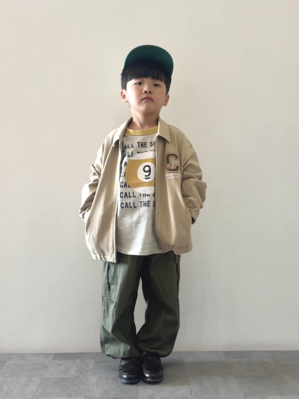 イエロー系のTシャツ/カットソー、ブラウン系のローファー、グリーン系のカーゴパンツを着用したキッズの冬コーディネートの3枚目の写真
