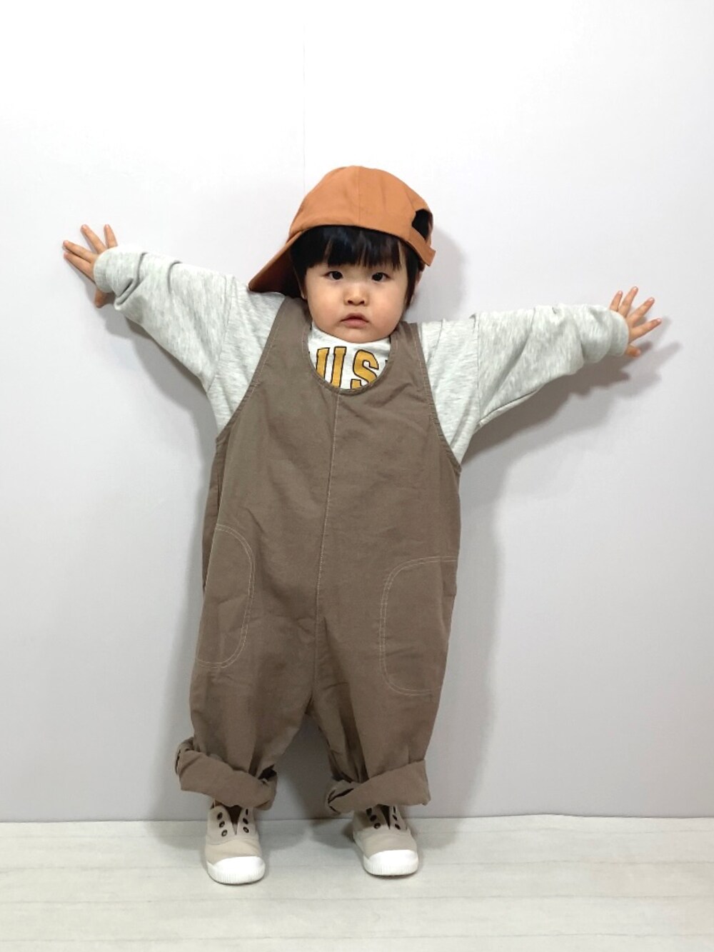 ホワイト系のスウェット、ブラウン系のオールインワン・サロペット、ベージュ系のシューズを着用したキッズの春コーディネートの2枚目の写真