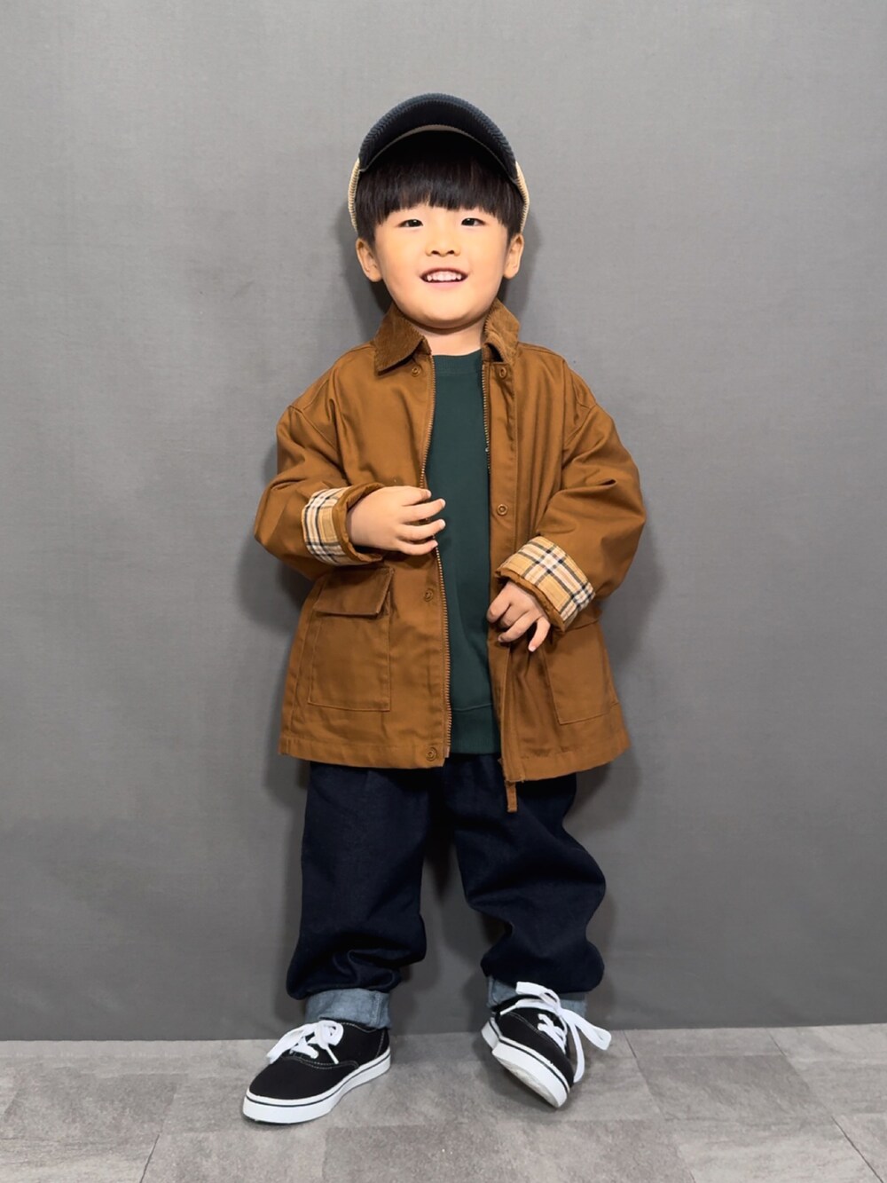 ブラウン系のジャケット/アウター、グリーン系のスウェット、ブルー系のデニムパンツを着用したキッズの秋コーディネートの5枚目の写真