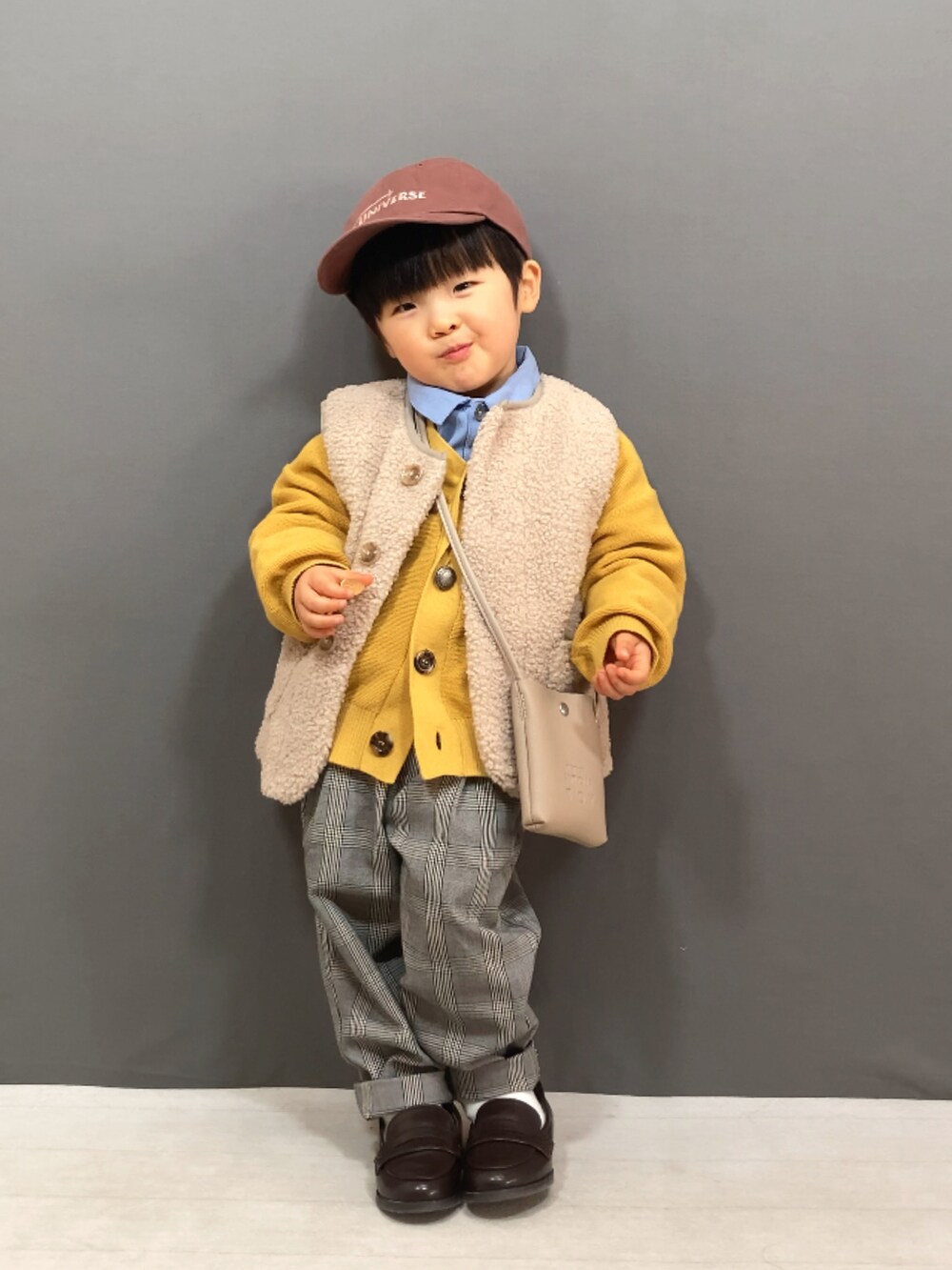 ベージュ系のベスト、イエロー系のカーディガン/ボレロ、ブルー系のシャツ/ブラウスを着用したキッズの冬コーディネートの2枚目の写真