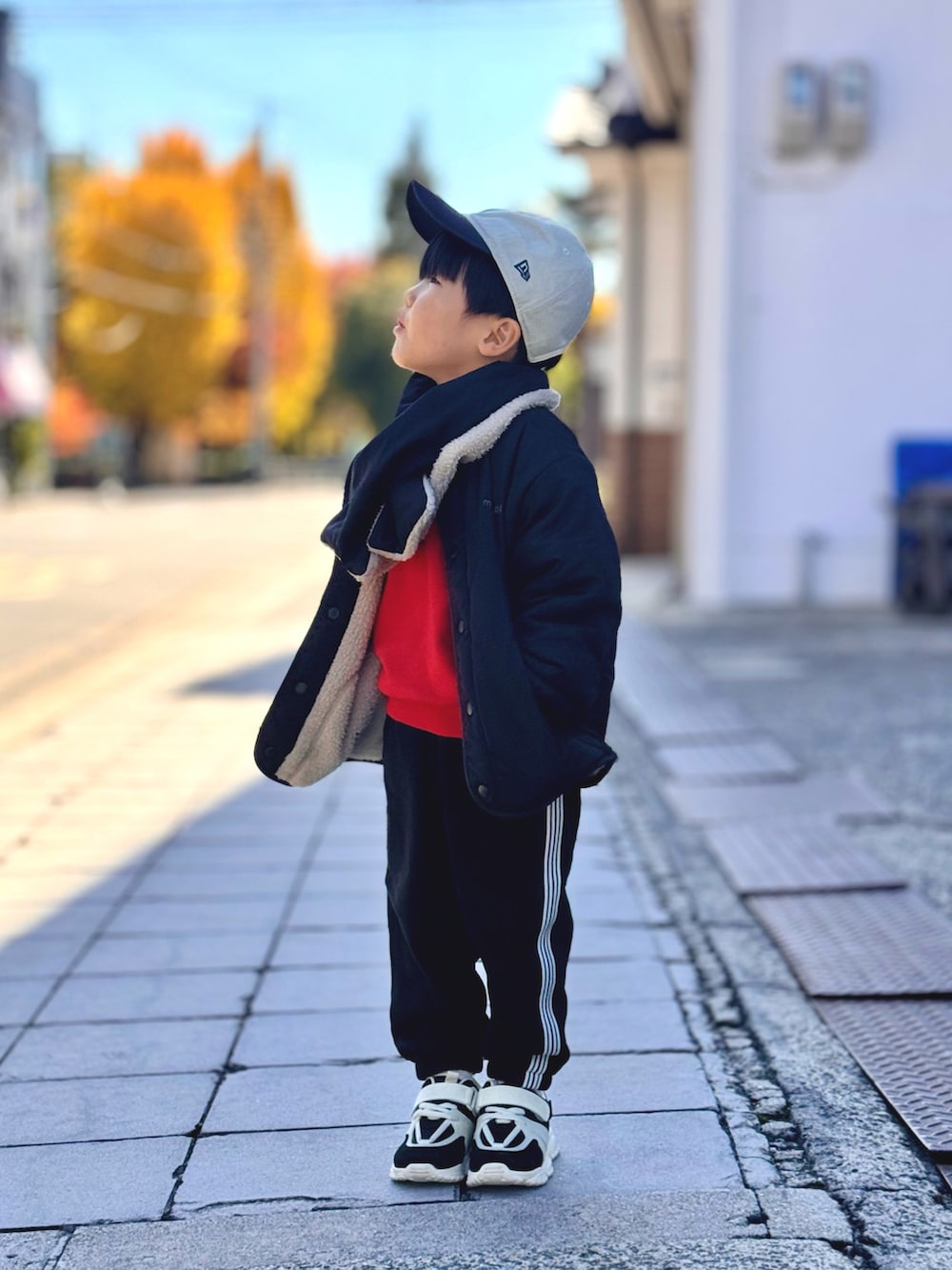 オレンジ系のスウェット、ブラック系のブルゾン、ブラック系のスウェットパンツを着用したキッズの秋コーディネートの3枚目の写真