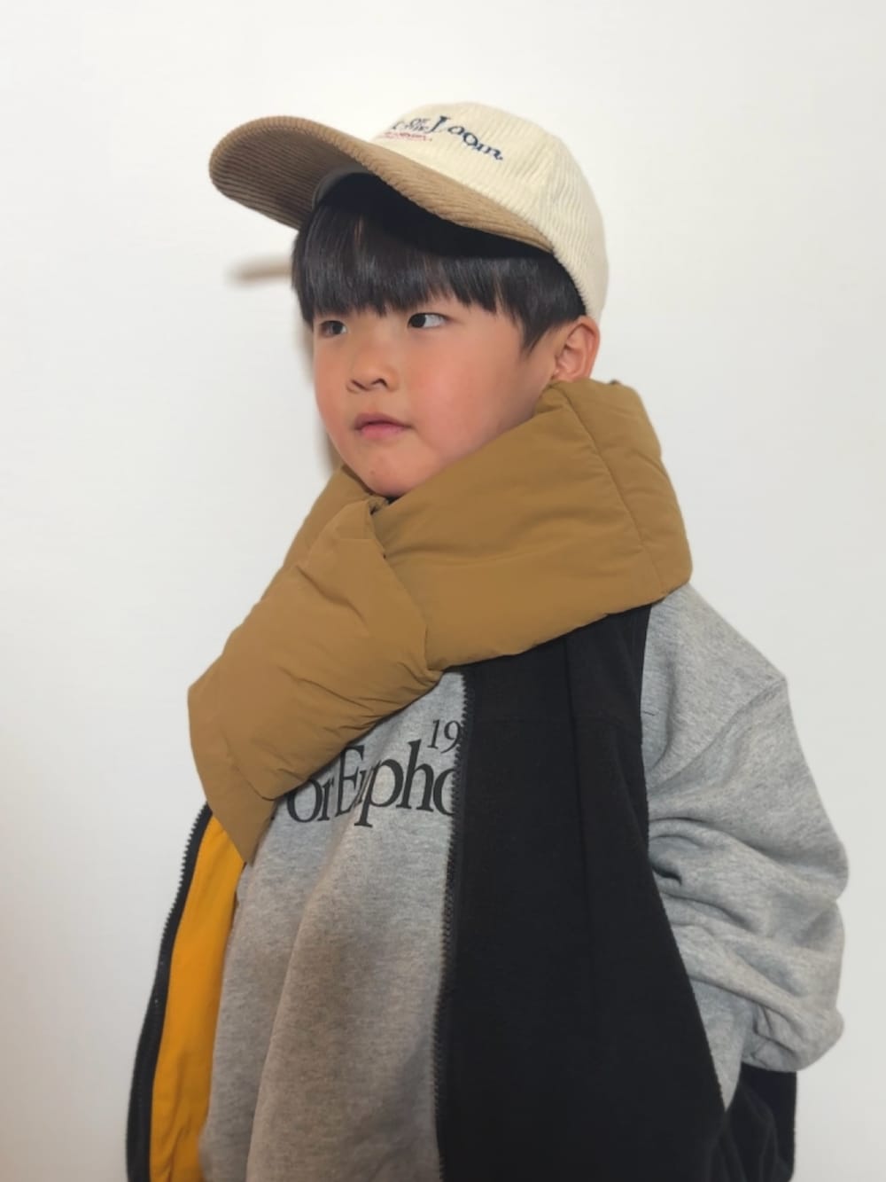 グレー系のスウェット、イエロー系のベスト、グレー系のスウェットパンツを着用したキッズの冬コーディネートの3枚目の写真