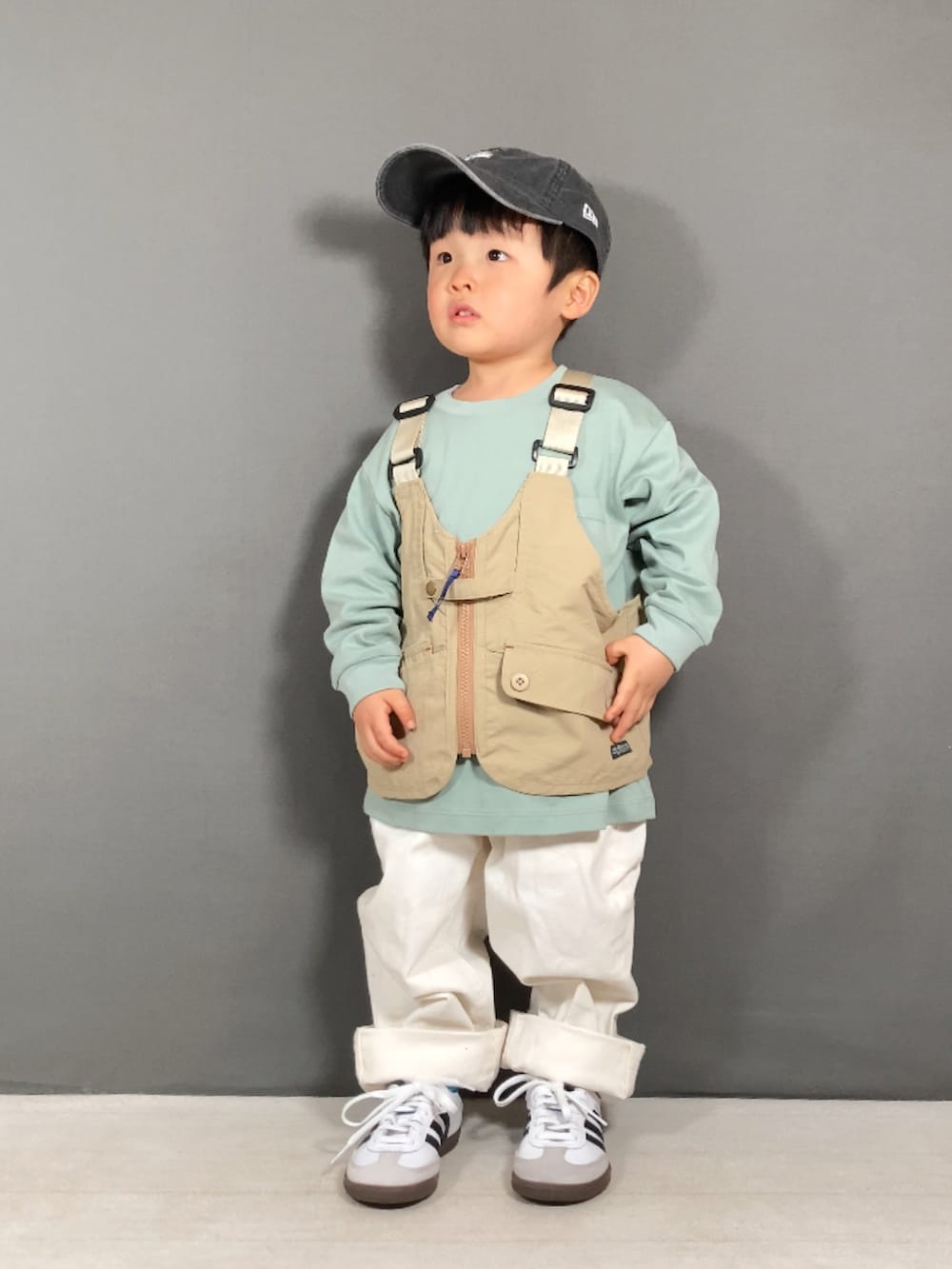 ベージュ系のベスト、グリーン系のTシャツ/カットソー、ホワイト系のパンツを着用したキッズの春コーディネートの4枚目の写真