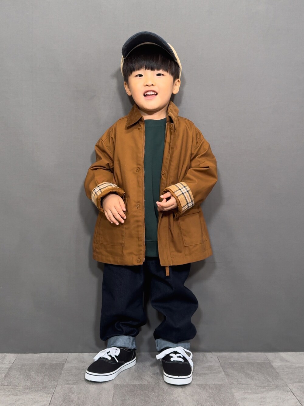 ブラウン系のジャケット/アウター、グリーン系のスウェット、ブルー系のデニムパンツを着用したキッズの秋コーディネートの4枚目の写真