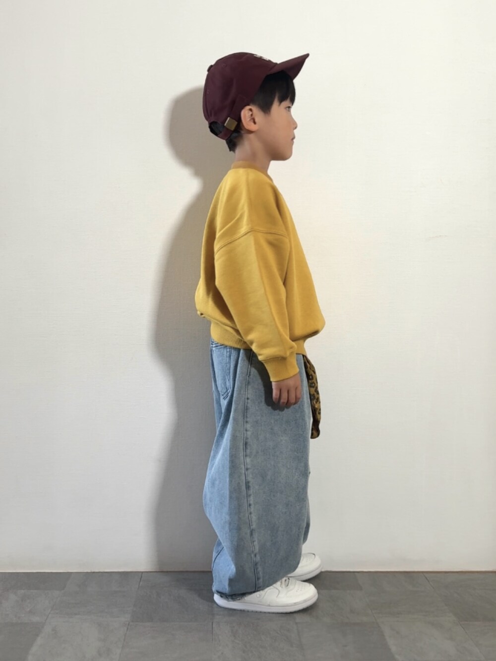 ブルー系のデニムパンツ、ホワイト系のスニーカー、イエロー系のスウェットを着用したキッズの秋コーディネートの3枚目の写真
