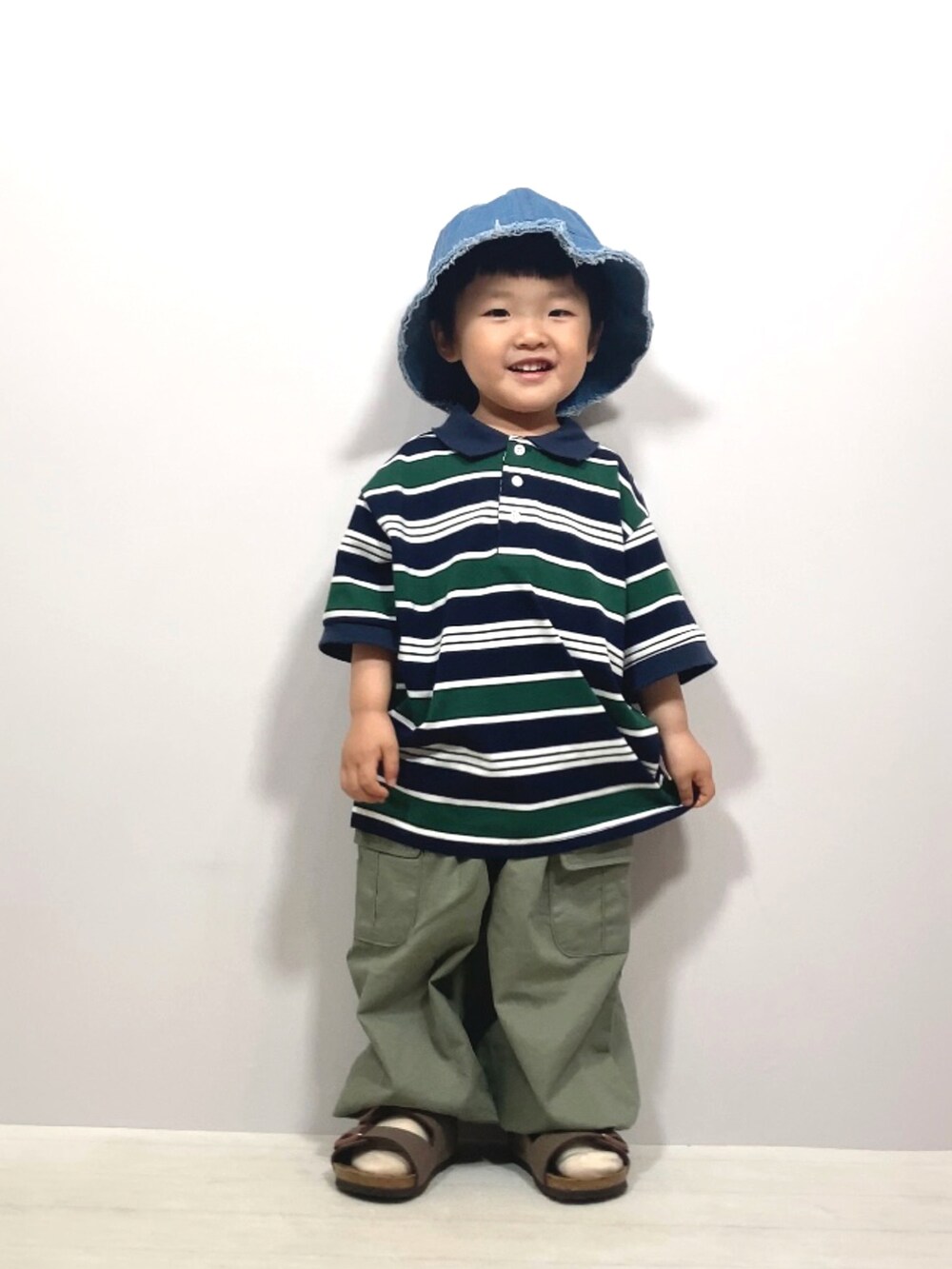 ブルー系のポロシャツ、グリーン系のカーゴパンツ、ブラウン系のサンダルを着用したキッズの夏コーディネートの3枚目の写真