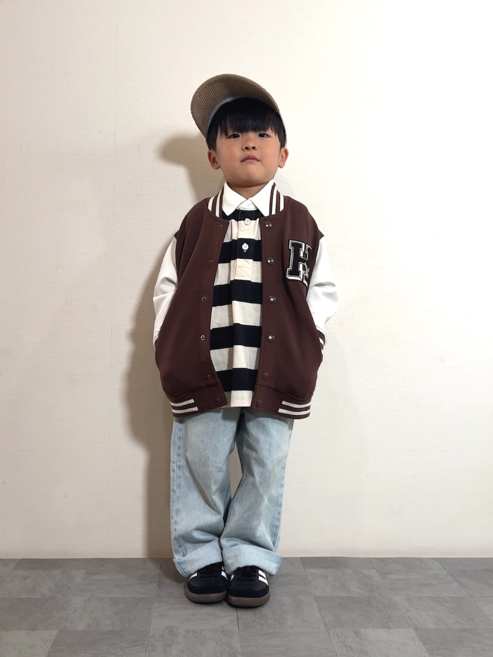 ブラック系のスニーカー、ホワイト系のポロシャツ、ブラウン系のスタジャンを着用したキッズの秋コーディネートの3枚目の写真