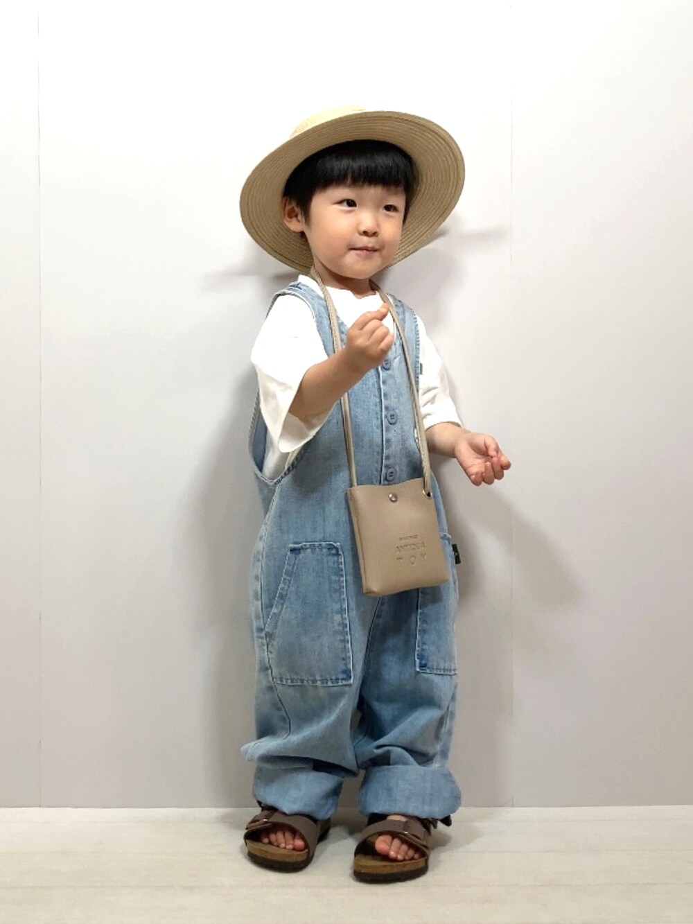 ホワイト系のTシャツ/カットソー、ブルー系のサロペット/オーバーオール、ベージュ系のショルダーバッグを着用したキッズの夏コーディネートの3枚目の写真