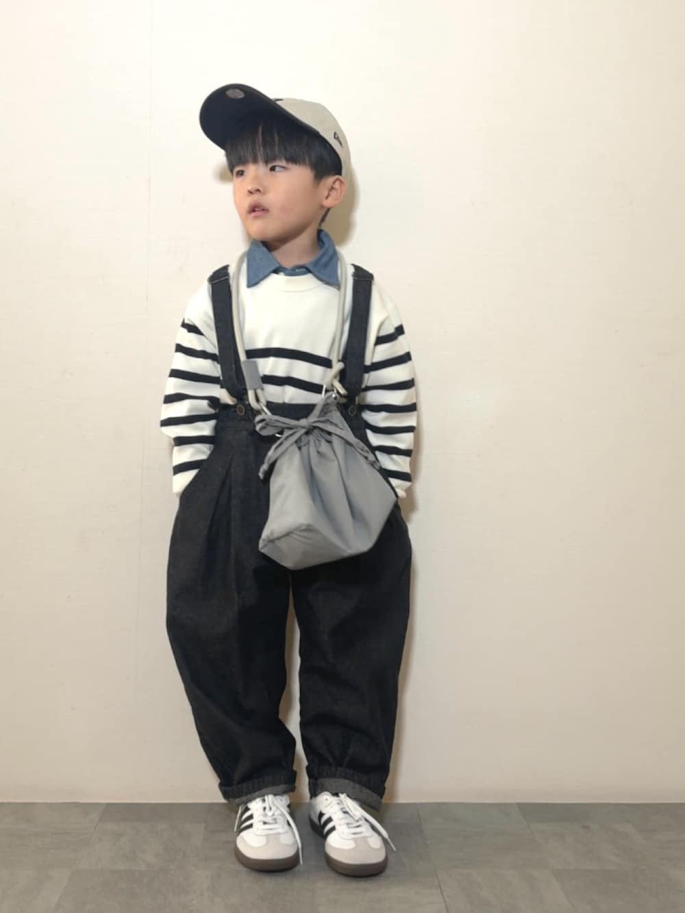 グレー系のショルダーバッグ、ブラック系のサロペット/オーバーオール、ホワイト系のスニーカーを着用したキッズの冬コーディネートの3枚目の写真