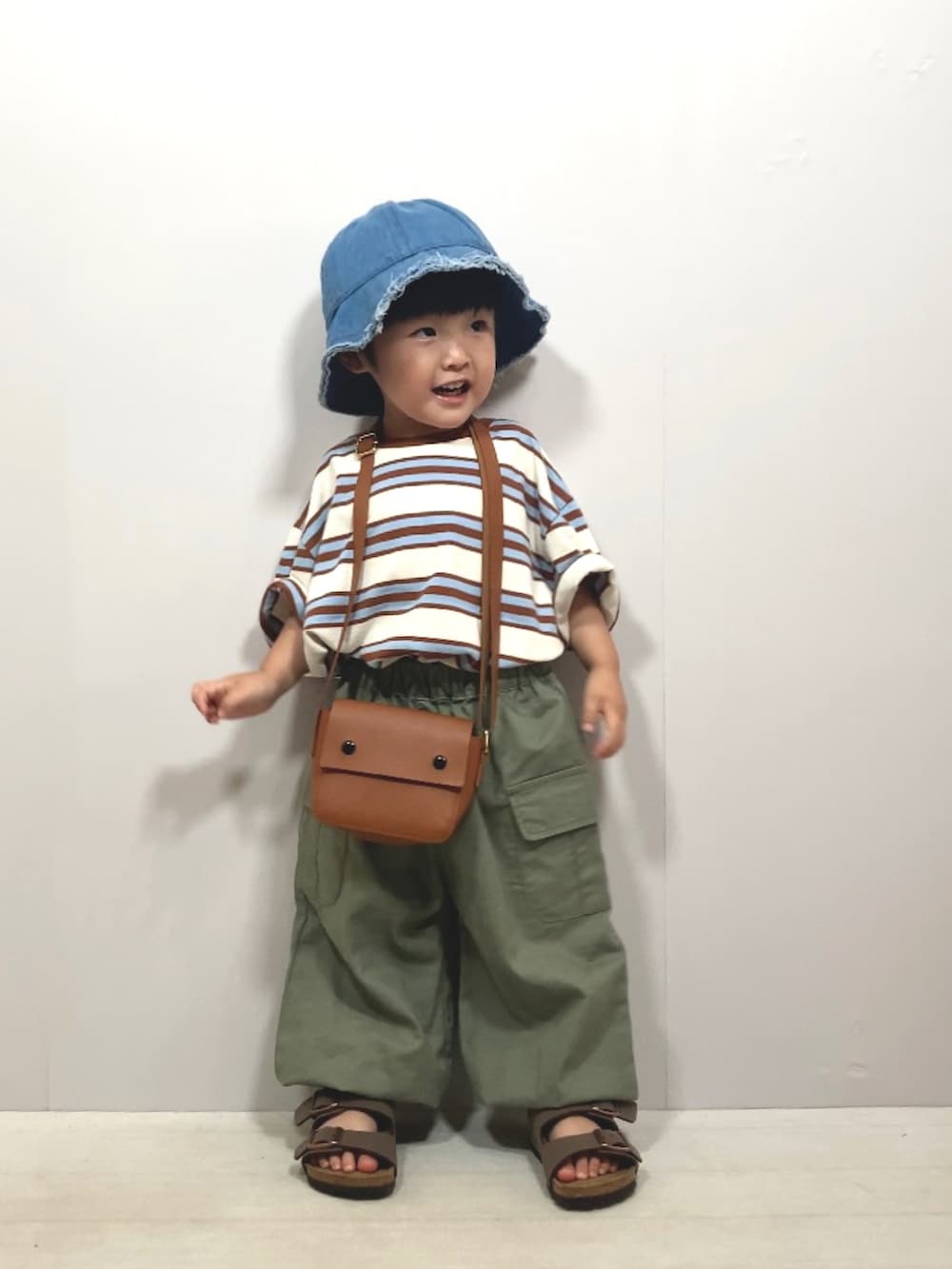 ベージュ系のTシャツ/カットソー、グリーン系のカーゴパンツ、ブラウン系のショルダーバッグを着用したキッズの夏コーディネートの2枚目の写真