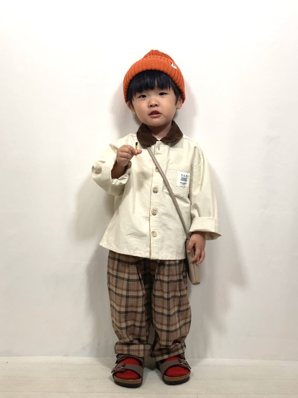 ホワイト系のジャケット/アウター、ブラウン系のパンツ、ベージュ系のショルダーバッグを着用したキッズの秋コーディネートの3枚目の写真