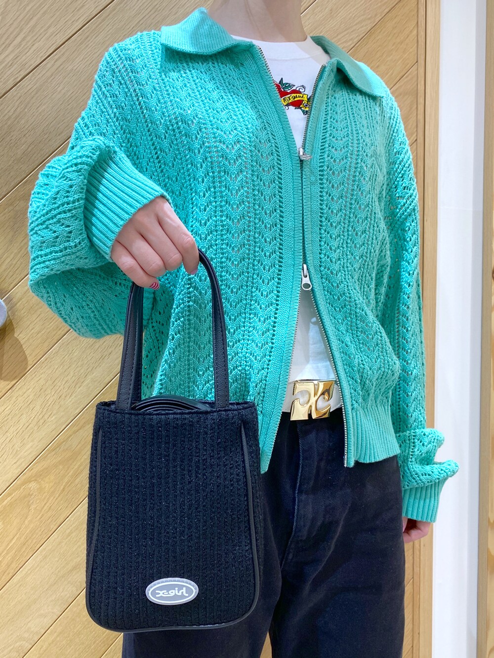 ブラック系のショルダーバッグ、グリーン系のカーディガン/ボレロ、ホワイト系のTシャツ/カットソーを着用したレディースの春コーディネートの5枚目の写真