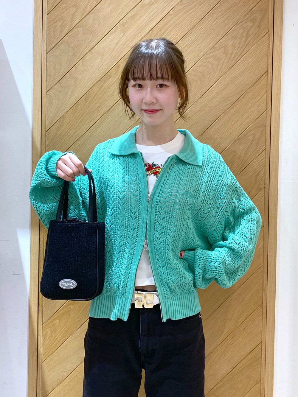 ブラック系のショルダーバッグ、グリーン系のカーディガン/ボレロ、ホワイト系のTシャツ/カットソーを着用したレディースの春コーディネートの4枚目の写真