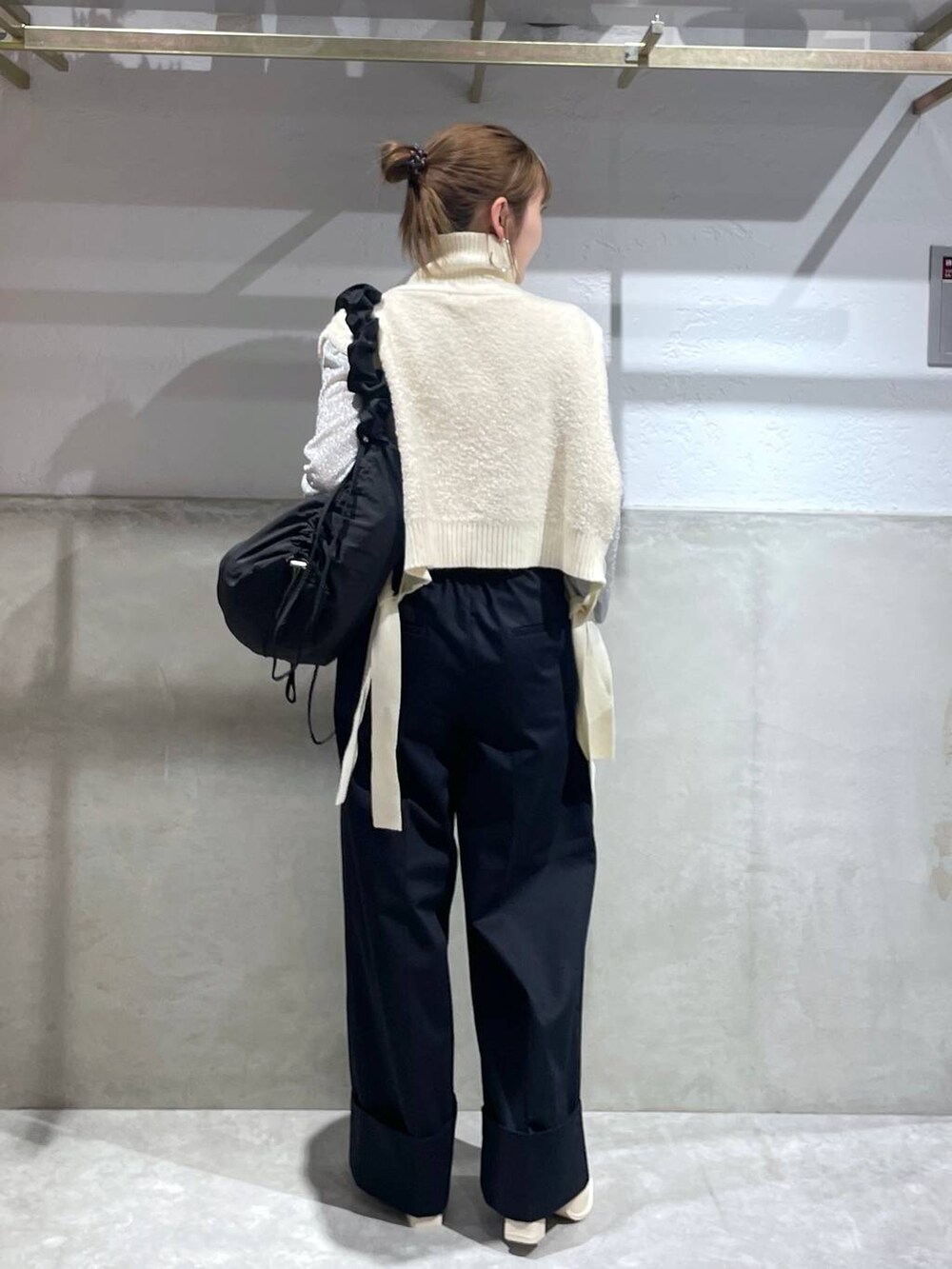 ブラック系のショルダーバッグ、ホワイト系のパンプス、ブルー系のチノパンツを着用したレディースの秋コーディネートの4枚目の写真