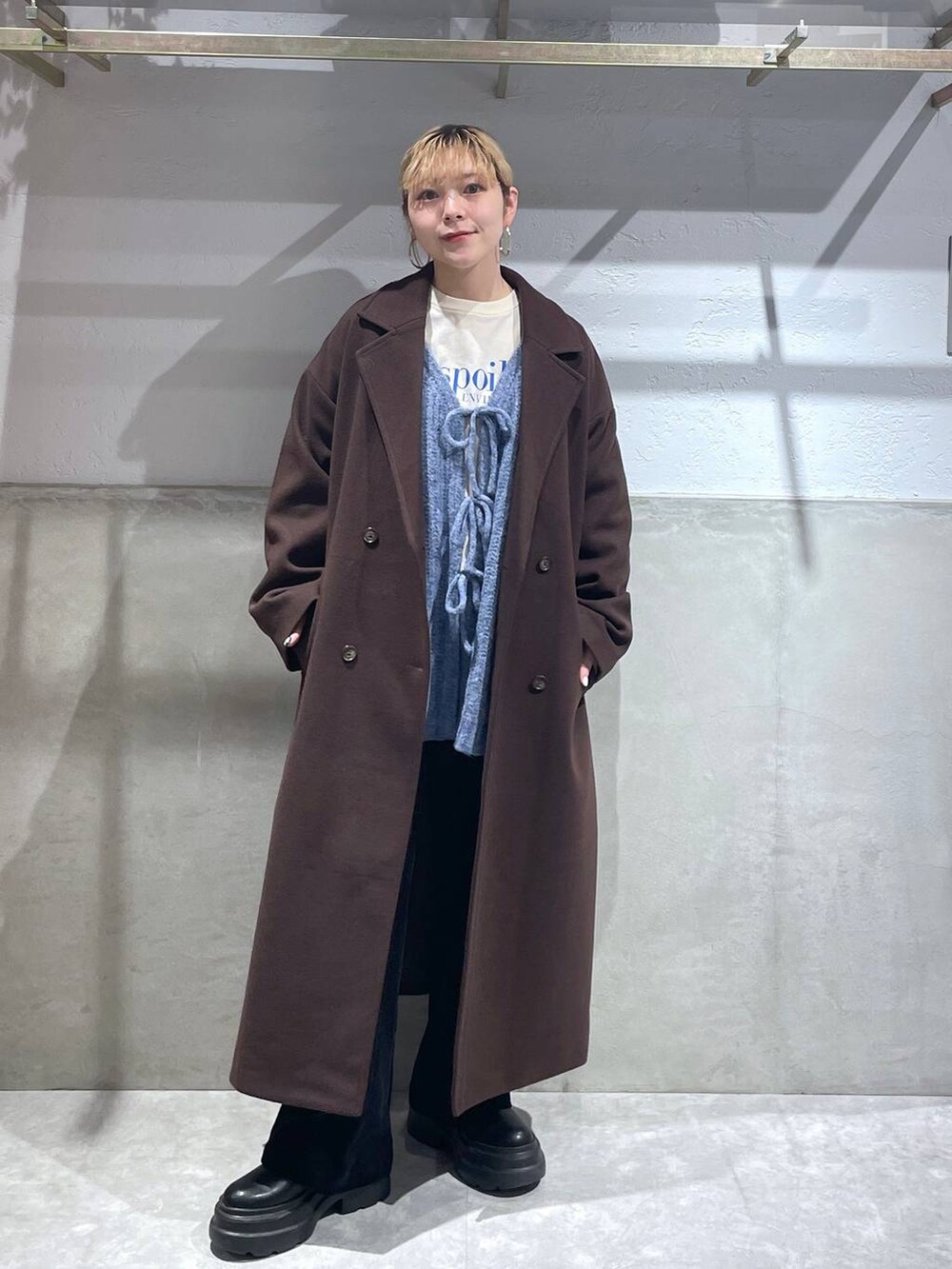 ブラウン系のトレンチコート、ブラック系のブーツ、ブラック系のデニムパンツを着用したレディースの冬コーディネートの4枚目の写真