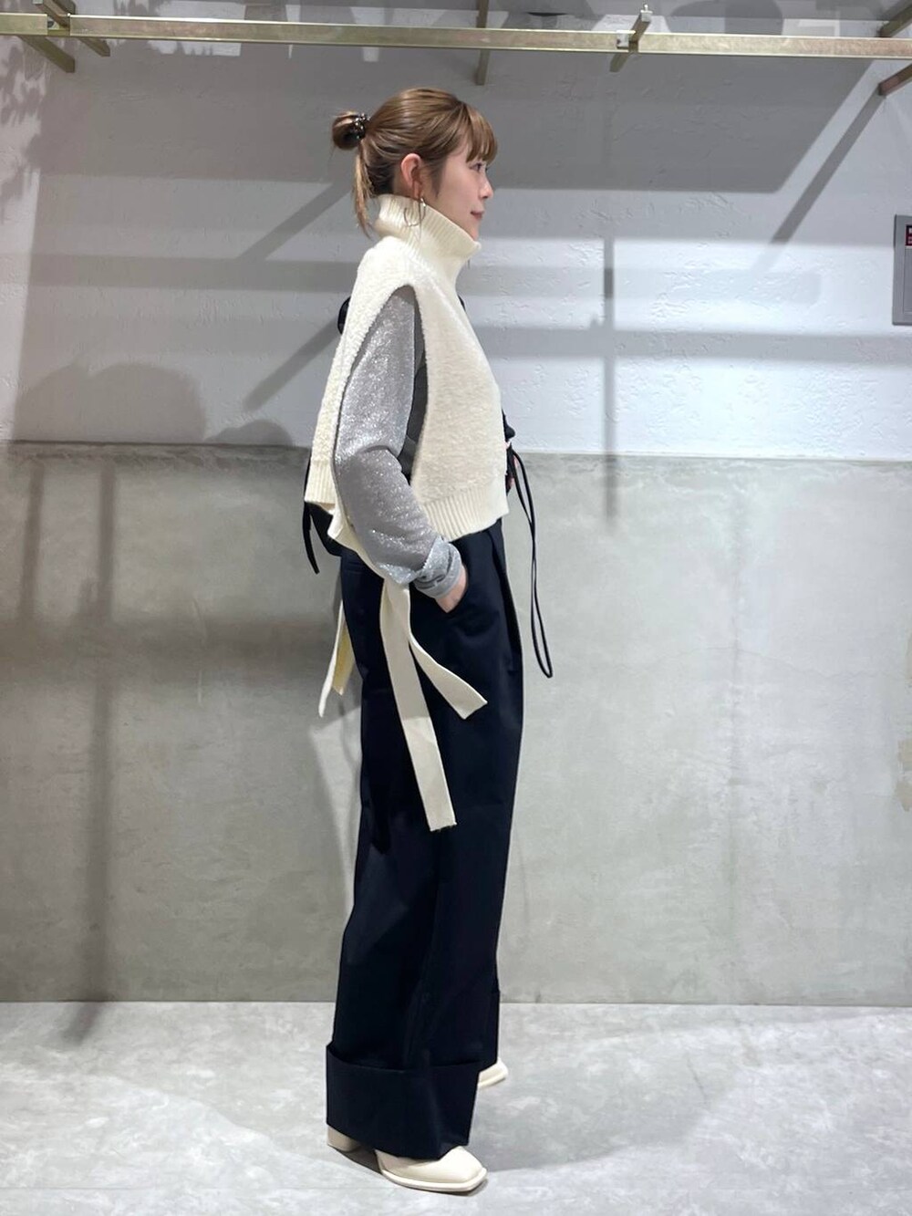 ブラック系のショルダーバッグ、ホワイト系のパンプス、ブルー系のチノパンツを着用したレディースの秋コーディネートの3枚目の写真