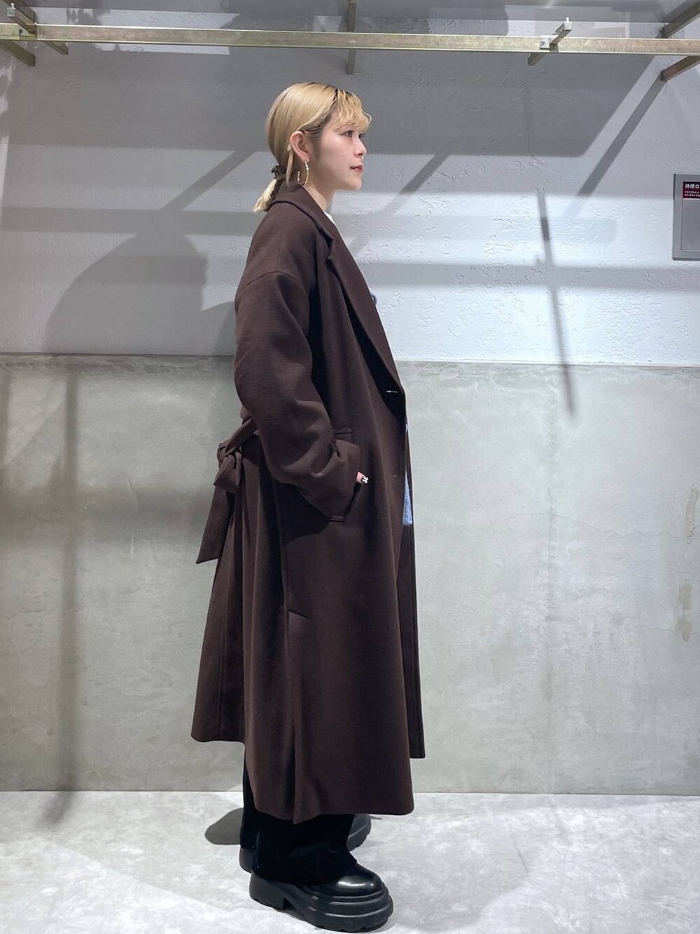 ブラウン系のトレンチコート、ブラック系のブーツ、ブラック系のデニムパンツを着用したレディースの冬コーディネートの2枚目の写真