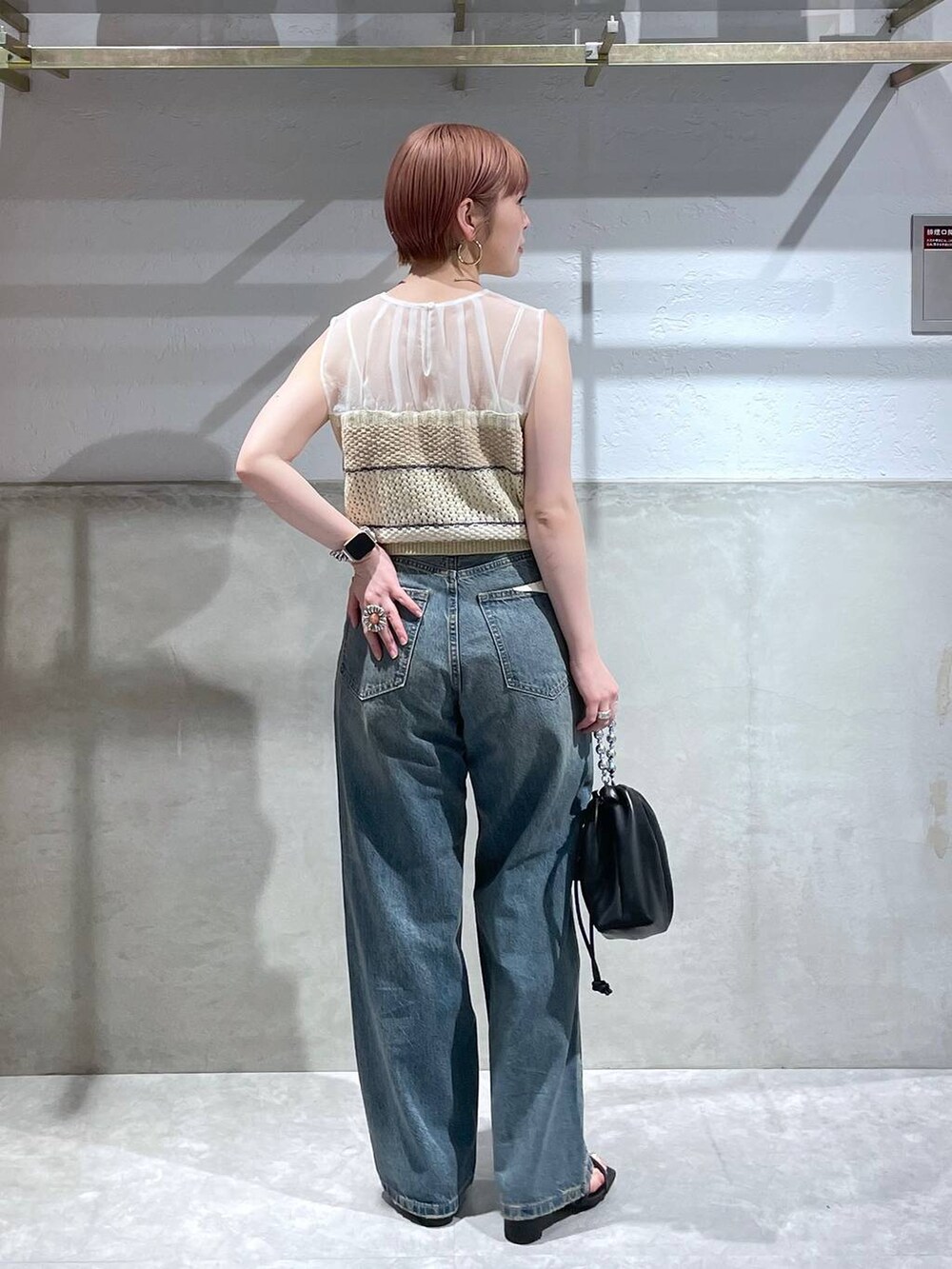 ベージュ系のニット/セーター、ブラック系のショルダーバッグ、ブルー系のデニムパンツを着用したレディースの夏コーディネートの4枚目の写真