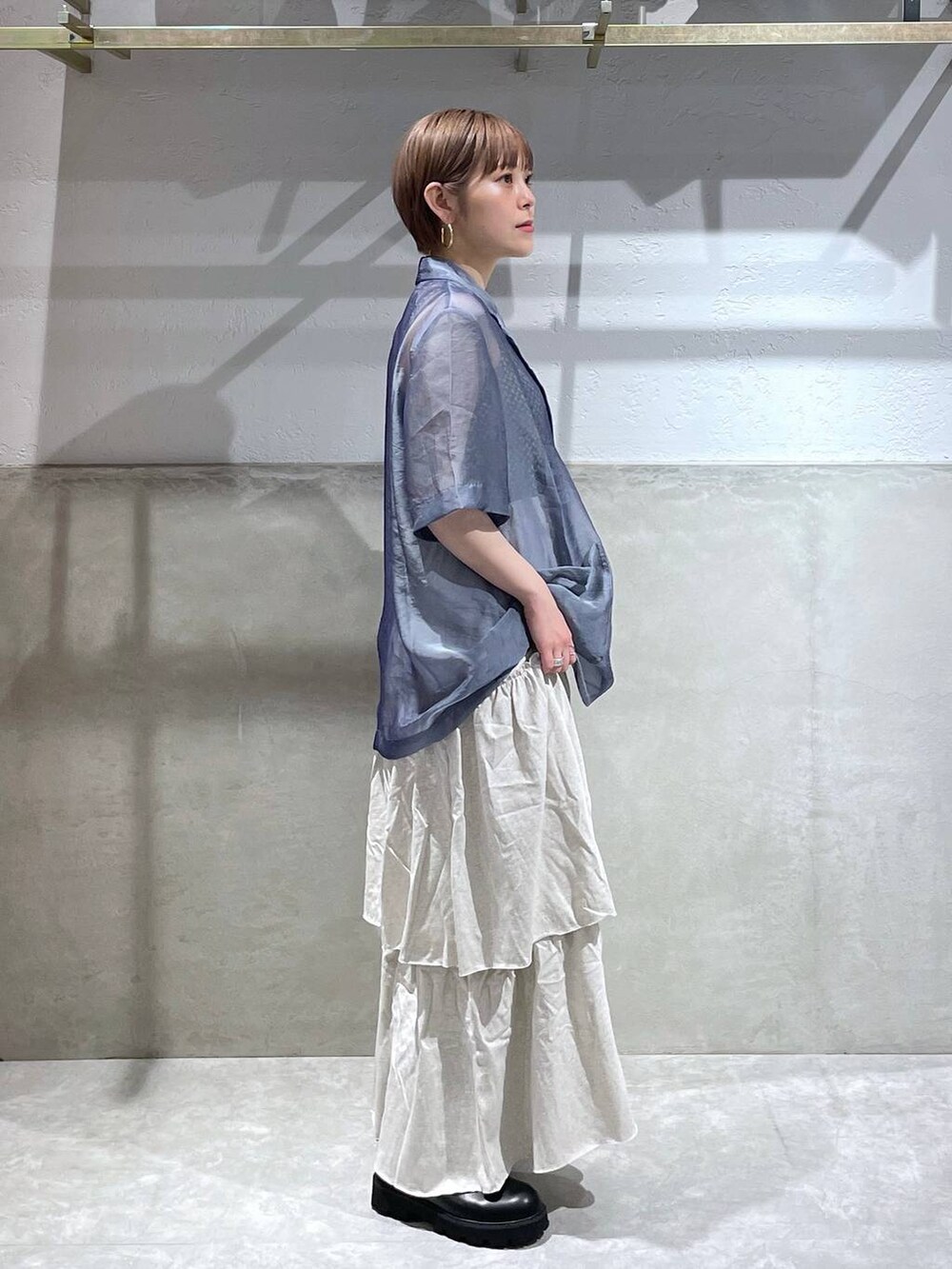 グレー系のスカート、ブラック系のショルダーバッグ、ブラック系のブーツを着用したレディースの夏コーディネートの4枚目の写真