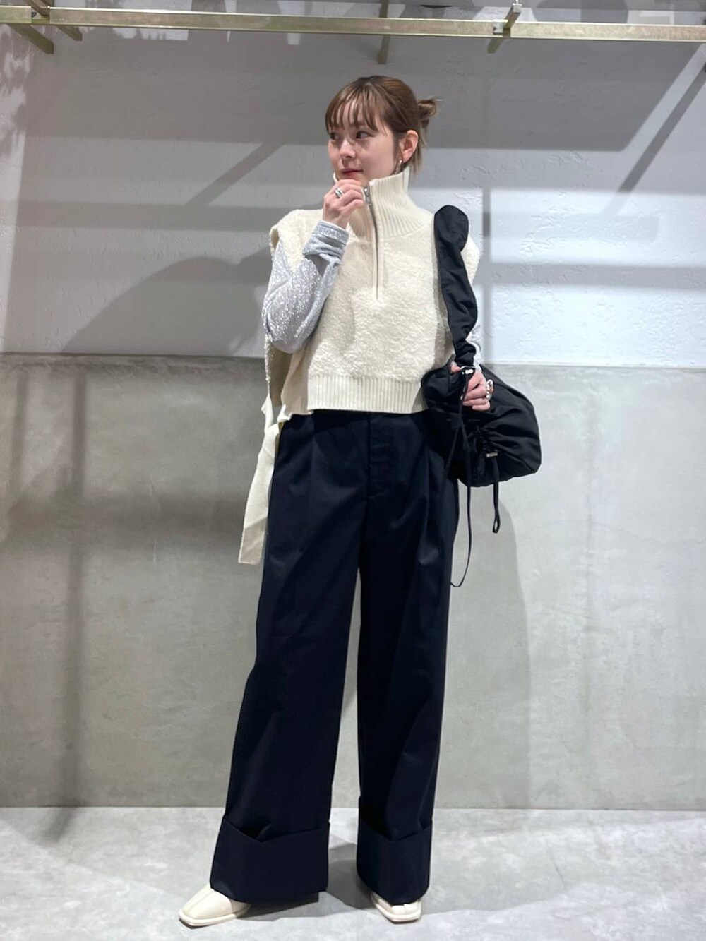 ブラック系のショルダーバッグ、ホワイト系のパンプス、ブルー系のチノパンツを着用したレディースの秋コーディネートの2枚目の写真