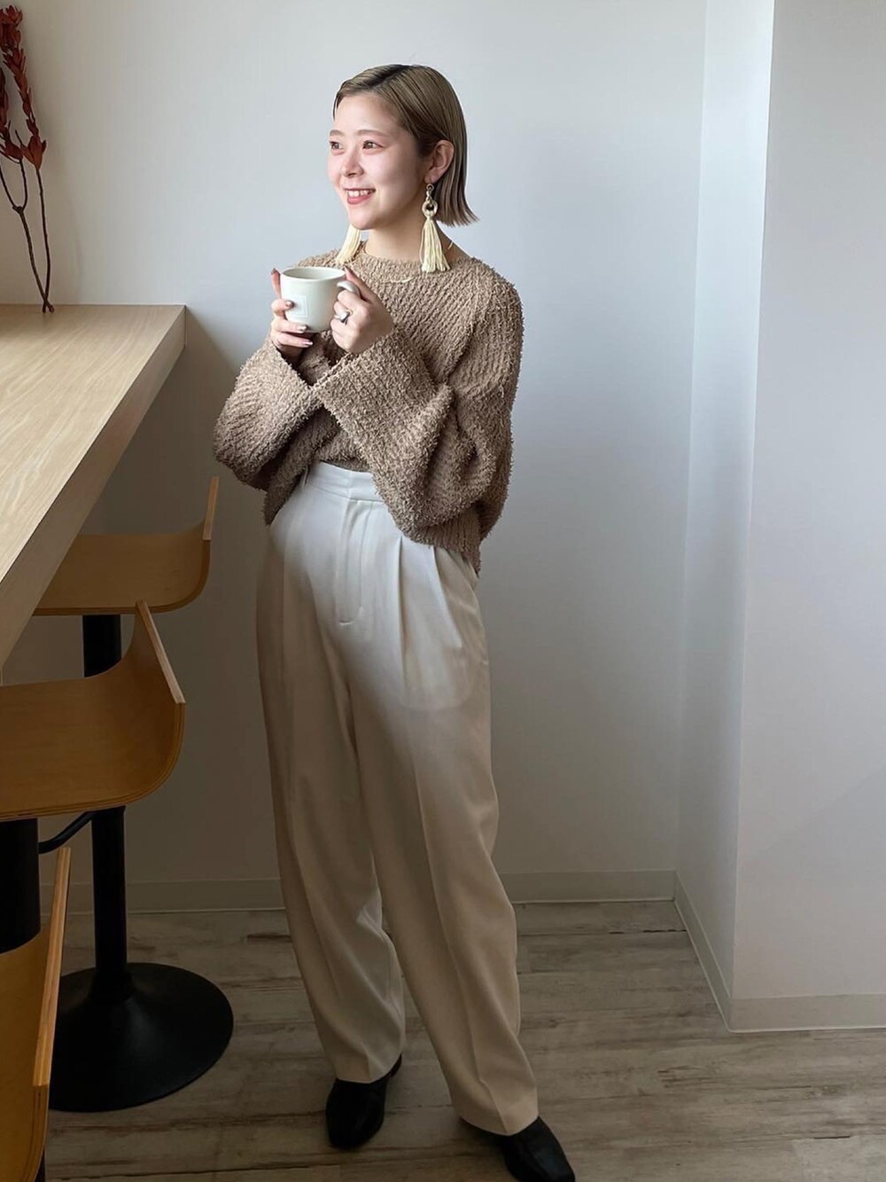 ベージュ系のニット/セーター、ホワイト系のその他パンツ、ブラック系のブーツを着用したレディースの冬コーディネートの2枚目の写真