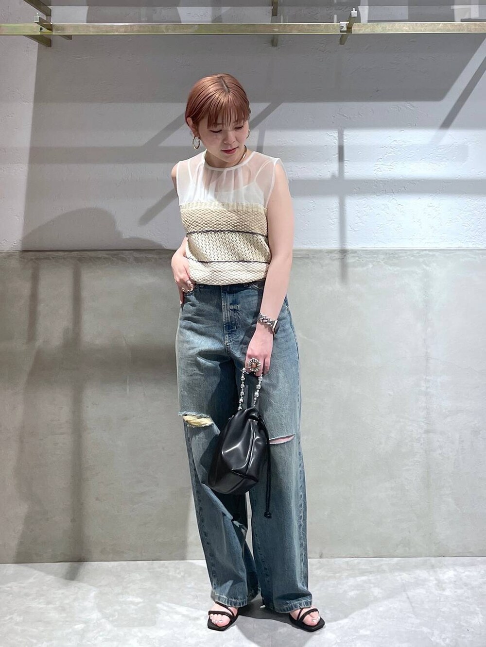 ベージュ系のニット/セーター、ブラック系のショルダーバッグ、ブルー系のデニムパンツを着用したレディースの夏コーディネートの3枚目の写真