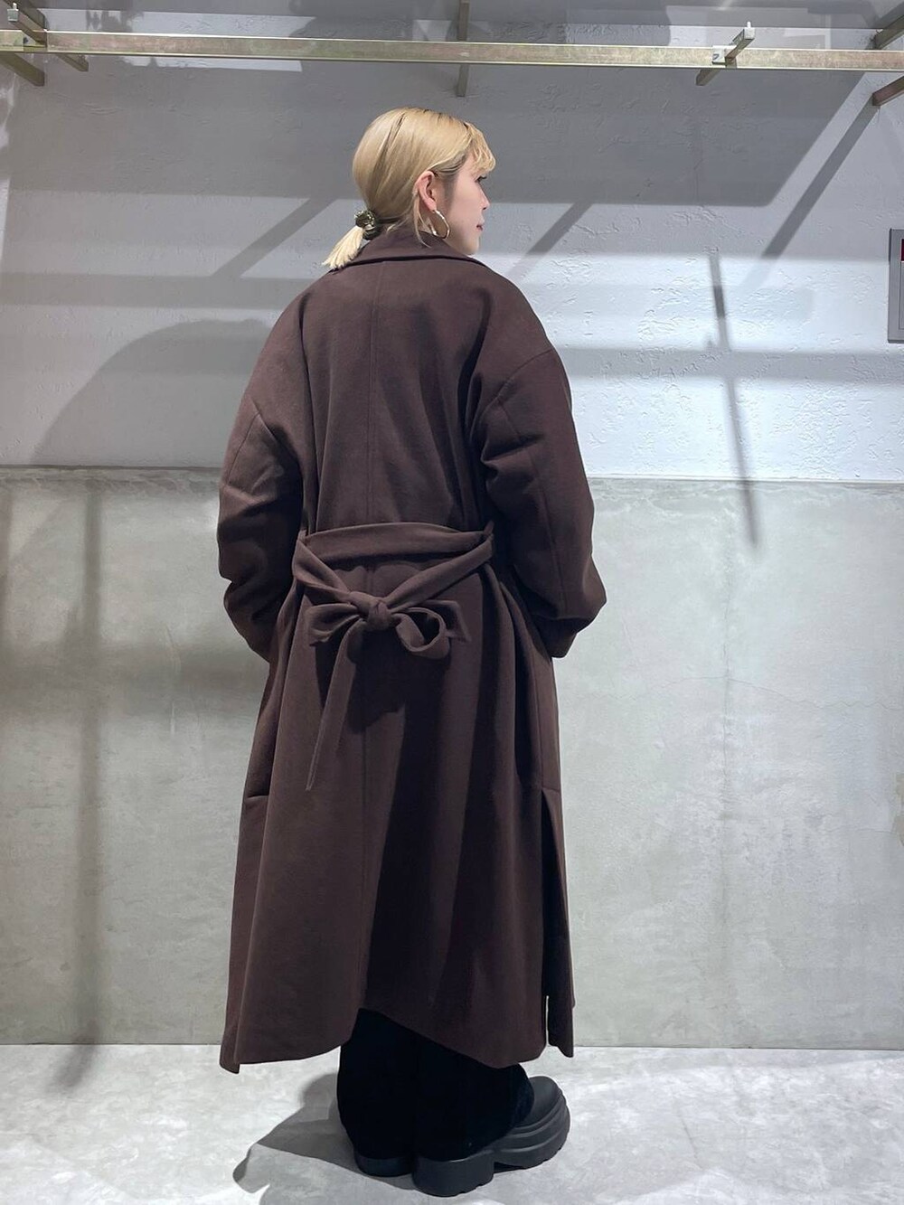 ブラウン系のトレンチコート、ブラック系のブーツ、ブラック系のデニムパンツを着用したレディースの冬コーディネートの3枚目の写真