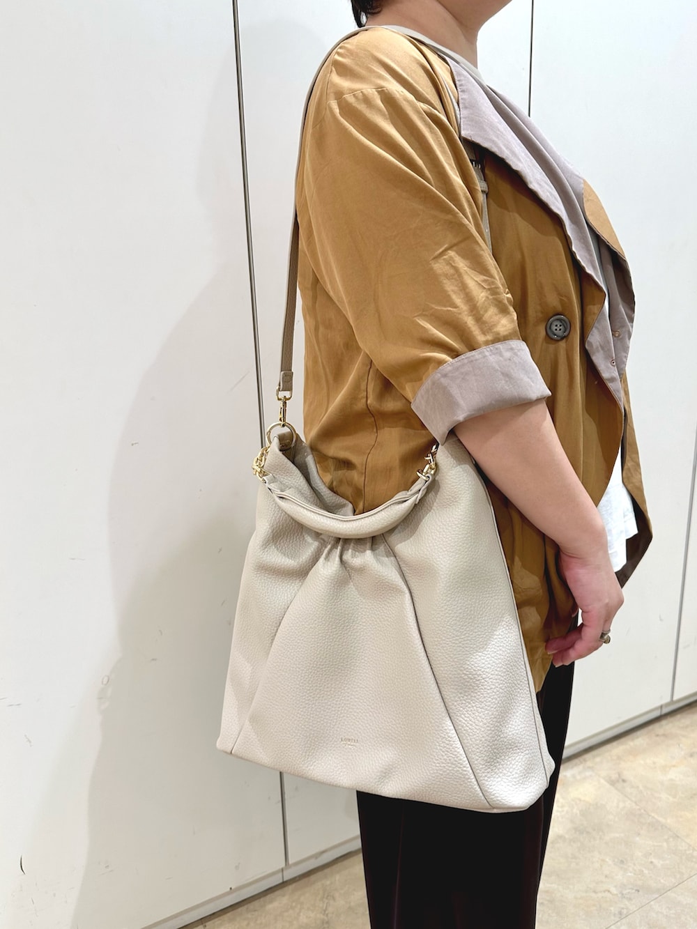 ホワイト系のトートバッグ、ブラウン系のパンプスを着用したレディースの秋コーディネートの5枚目の写真