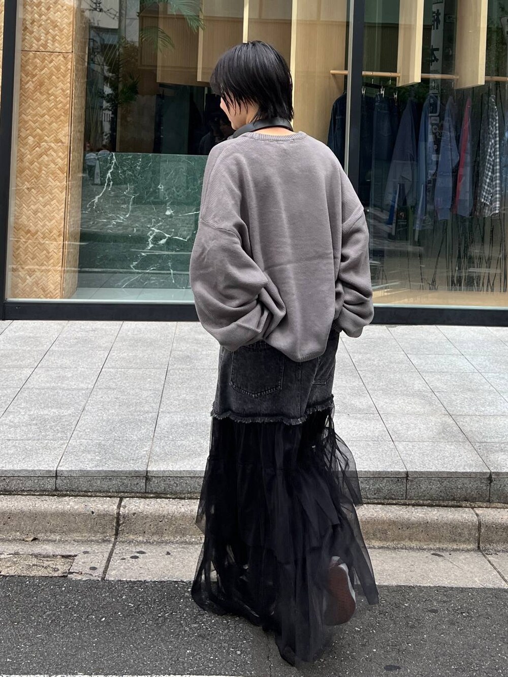 グレー系のニット/セーター、ブルー系のデニムスカートを着用したレディースの秋コーディネートの4枚目の写真