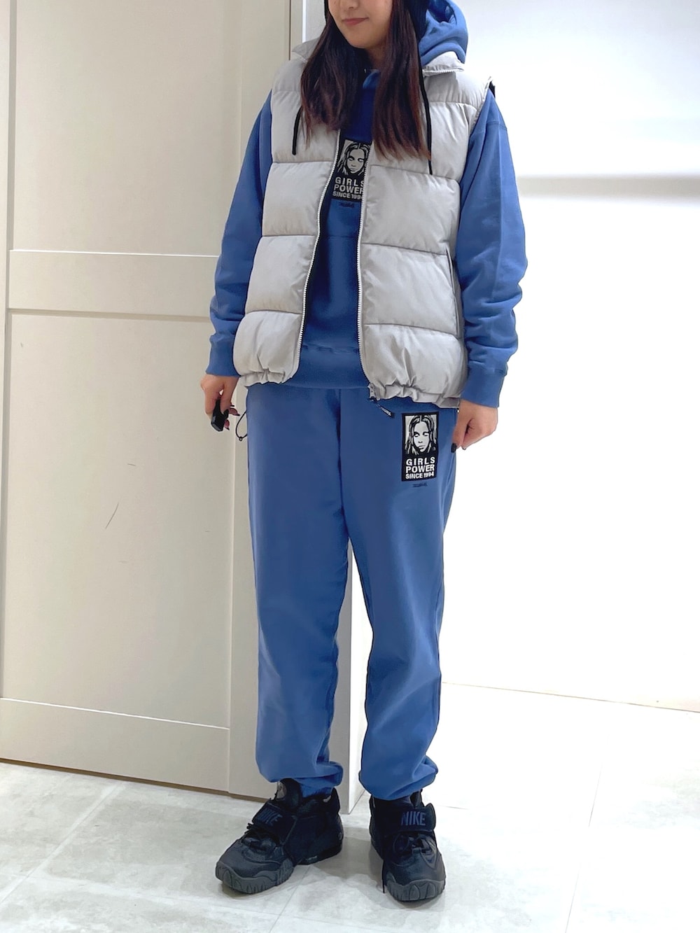 グレー系のダウンベスト、ブルー系のパーカー、ブルー系のスウェットパンツを着用したレディースの冬コーディネートの3枚目の写真