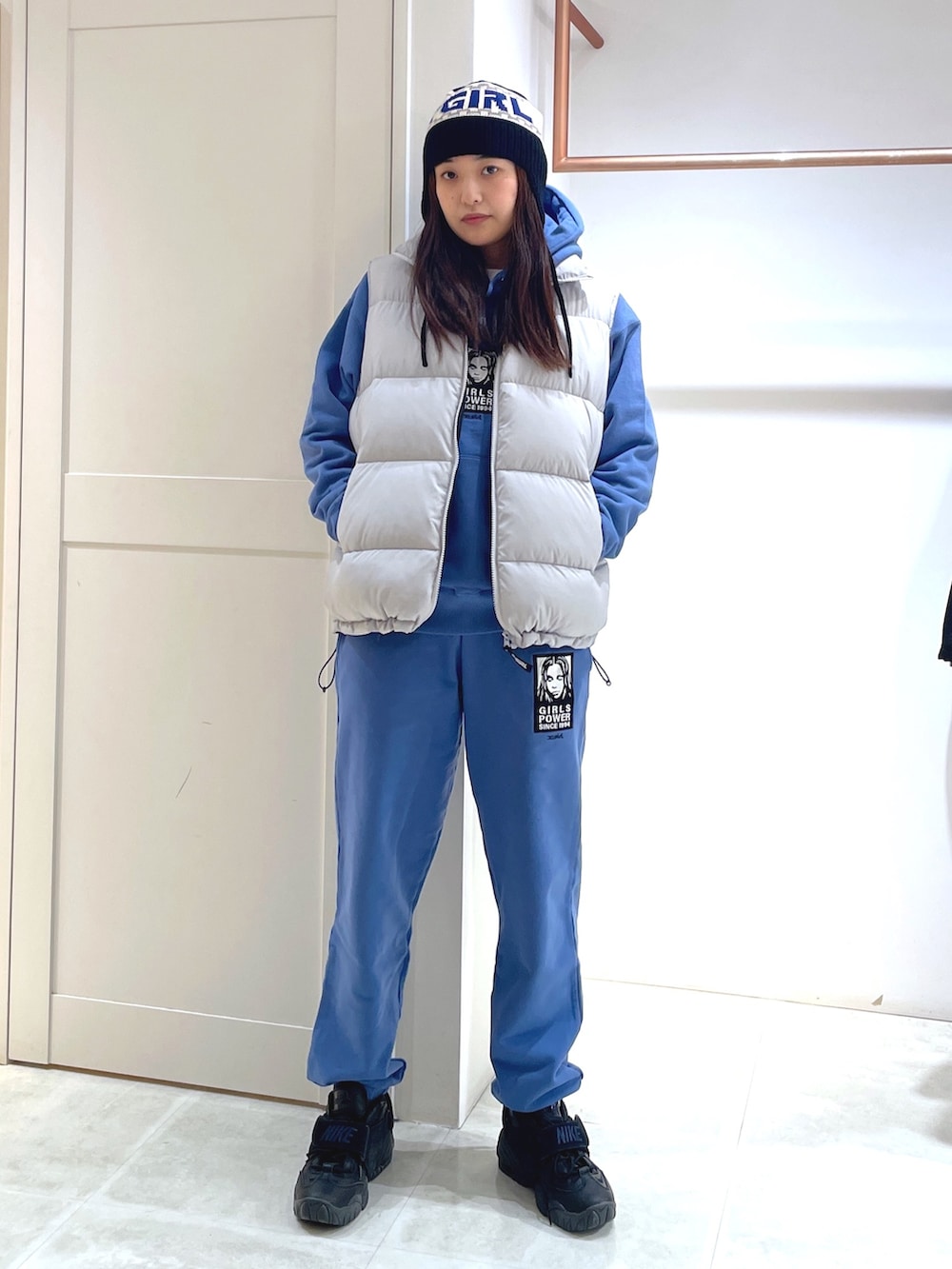 グレー系のダウンベスト、ブルー系のパーカー、ブルー系のスウェットパンツを着用したレディースの冬コーディネートの2枚目の写真