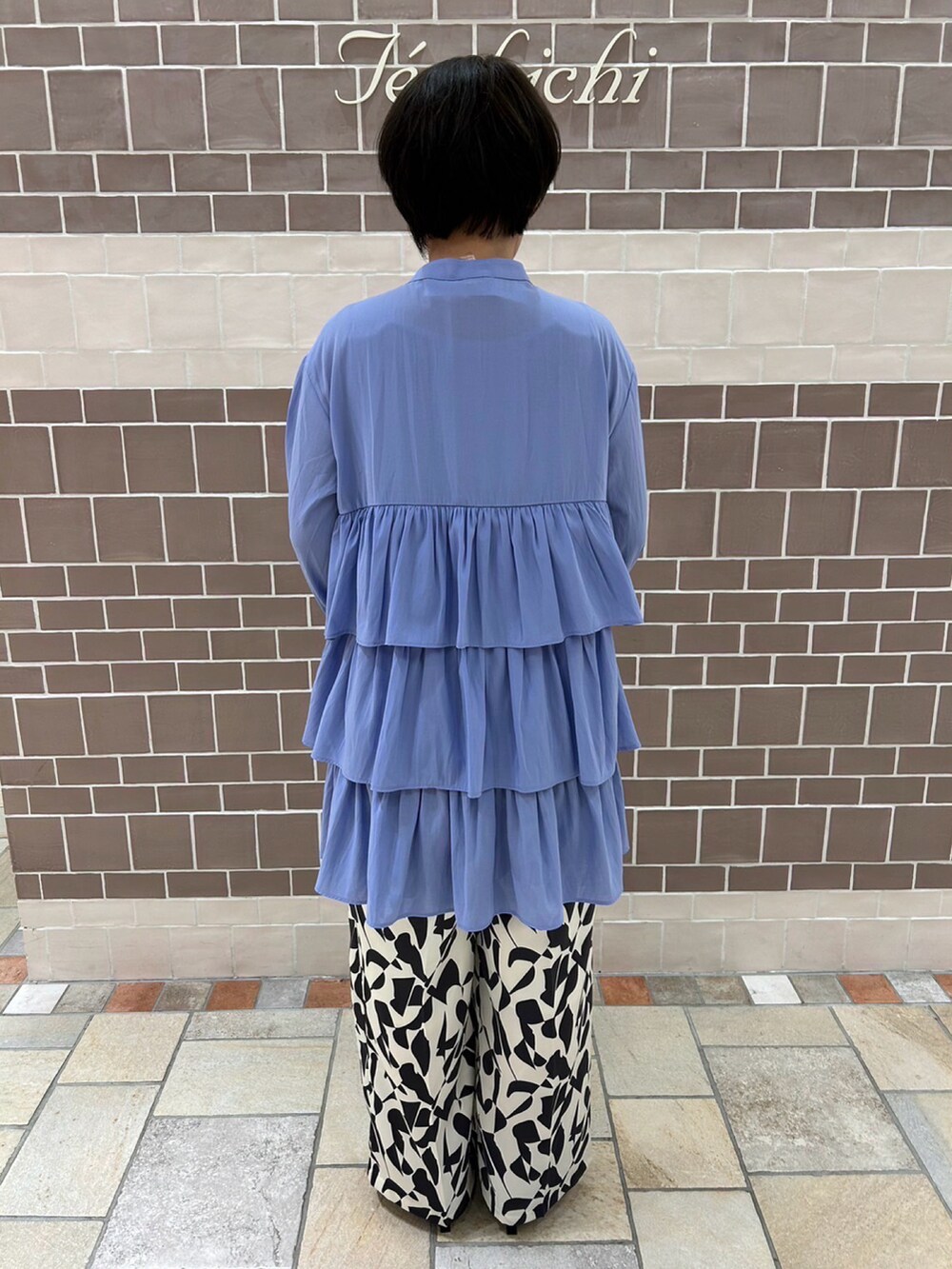 ブルー系のシャツ/ブラウス、ゴールド系のハンドバッグ、ホワイト系のパンツを着用したレディースの冬コーディネートの4枚目の写真