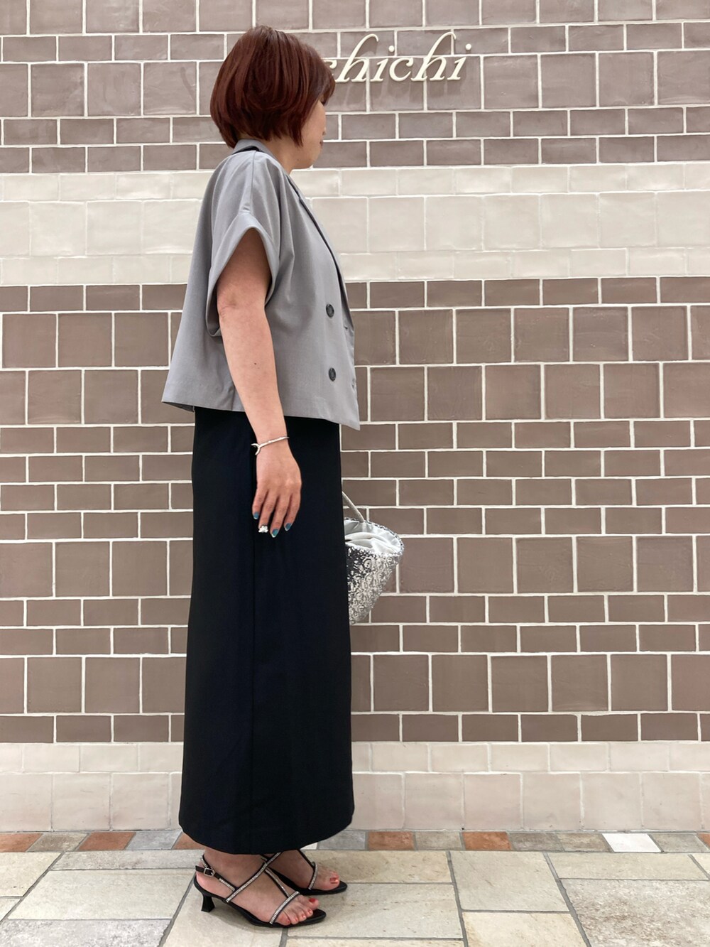 ブラック系のワンピース/ドレス、グレー系のノーカラージャケット、シルバー系のハンドバッグを着用したレディースの夏コーディネートの3枚目の写真