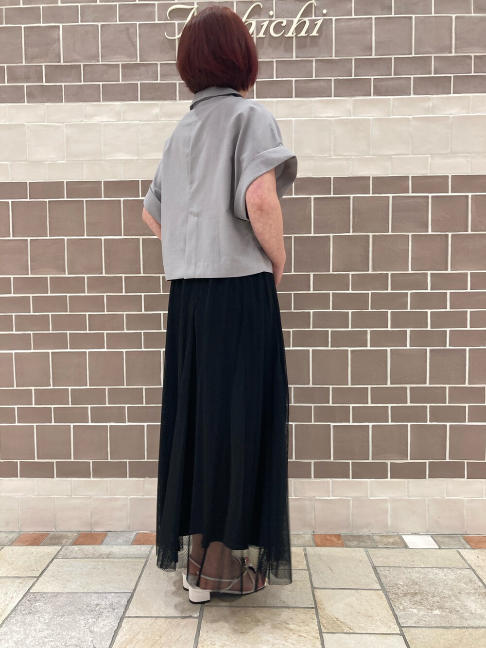 グレー系のノーカラージャケット、ブラック系のスカート、ホワイト系のサンダルを着用したレディースの夏コーディネートの4枚目の写真