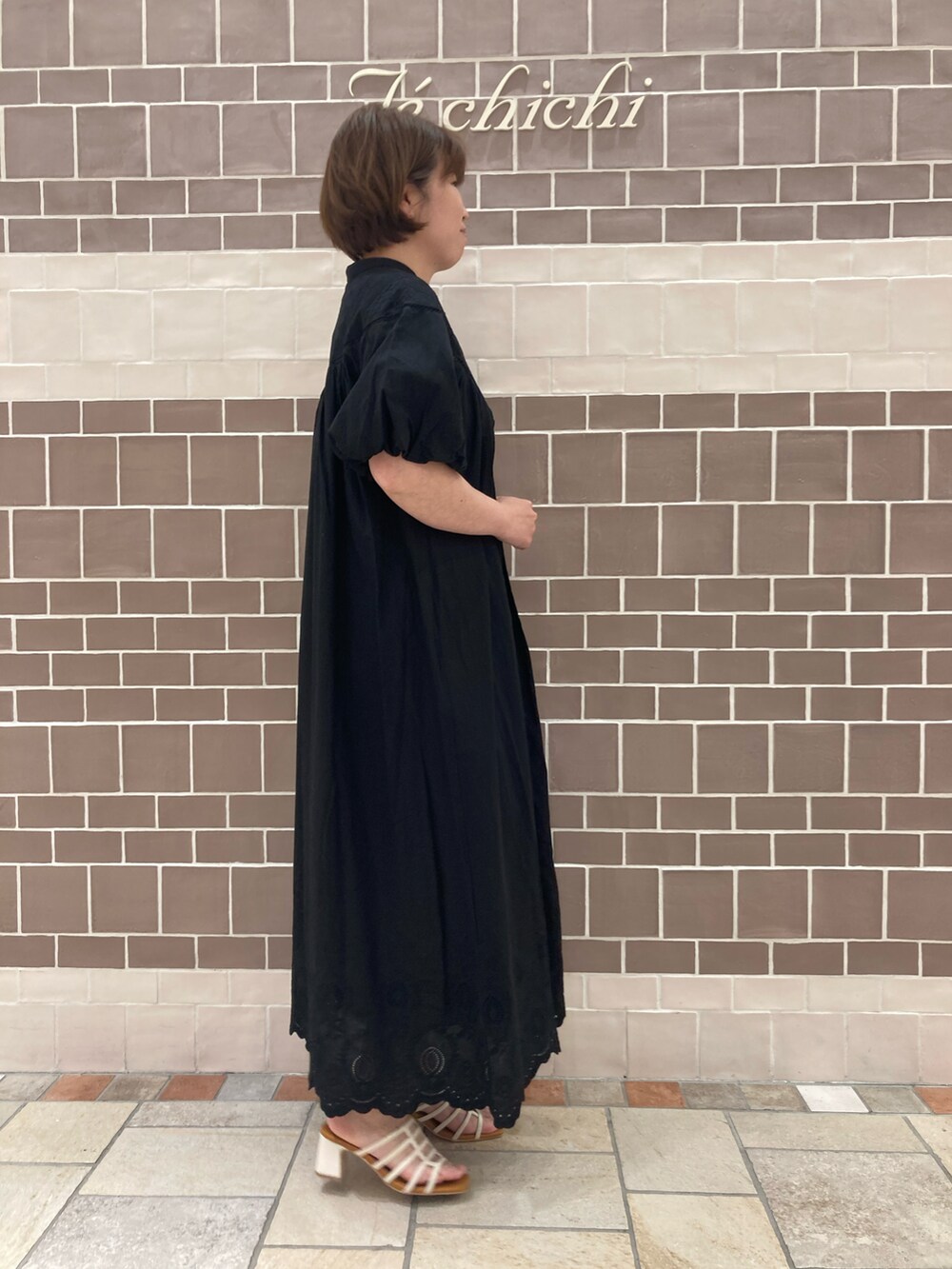 ブラック系のワンピース、ホワイト系のサンダルを着用したレディースの春コーディネートの3枚目の写真