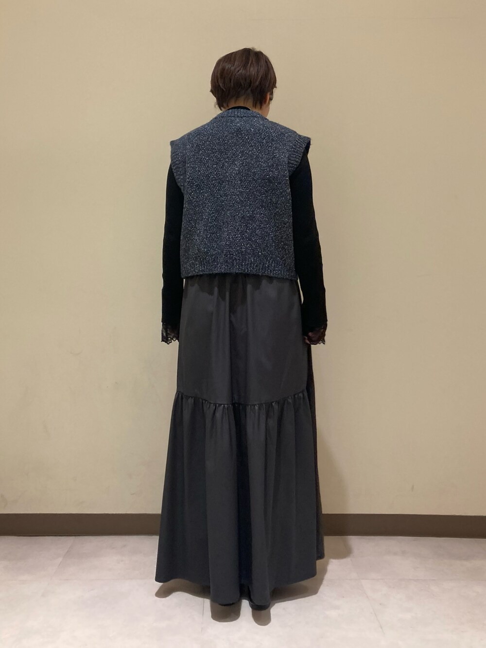ブルー系のベスト、ブラック系のニット/セーター、グレー系のスカートを着用したレディースの冬コーディネートの4枚目の写真