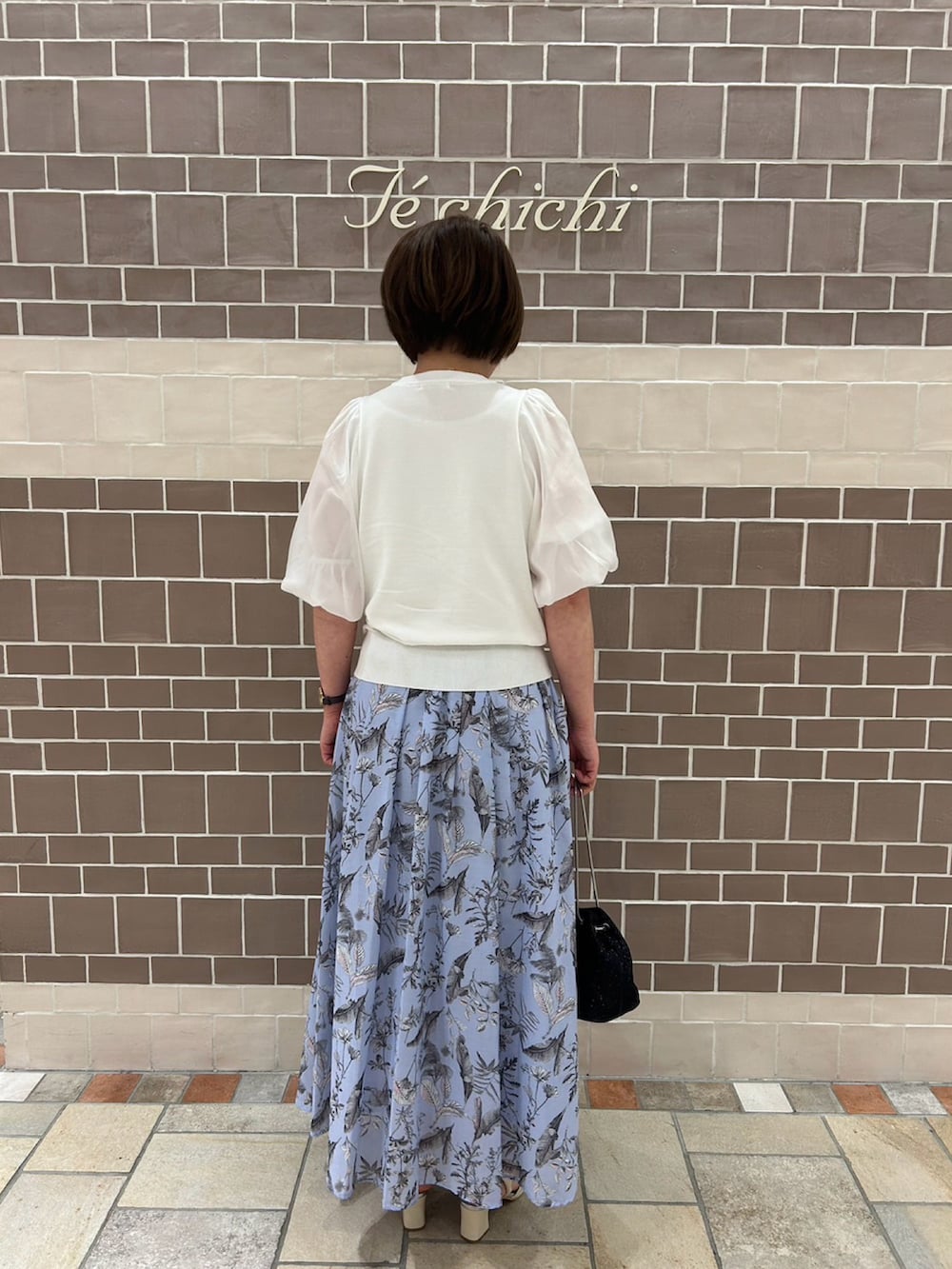 ホワイト系のニット/セーター、ブルー系のスカート、ホワイト系のサンダルを着用したレディースの春コーディネートの3枚目の写真