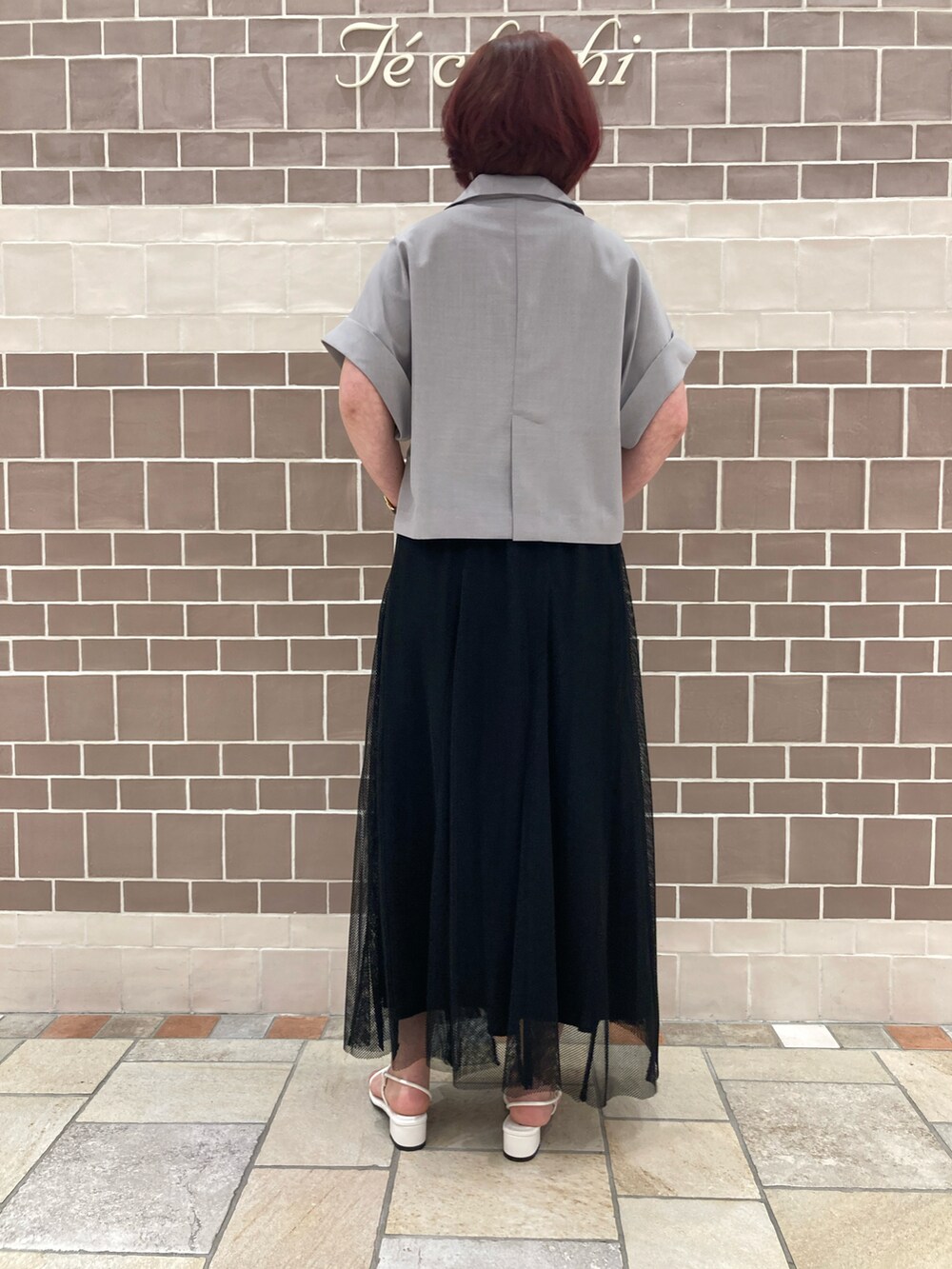 グレー系のノーカラージャケット、ブラック系のスカート、ホワイト系のサンダルを着用したレディースの夏コーディネートの5枚目の写真