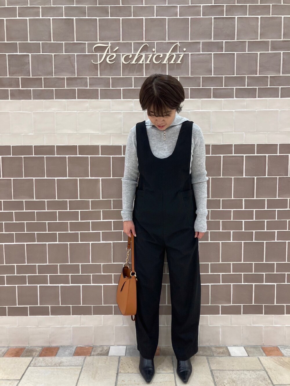 イエロー系のハンドバッグを着用したレディースの秋コーディネートの2枚目の写真