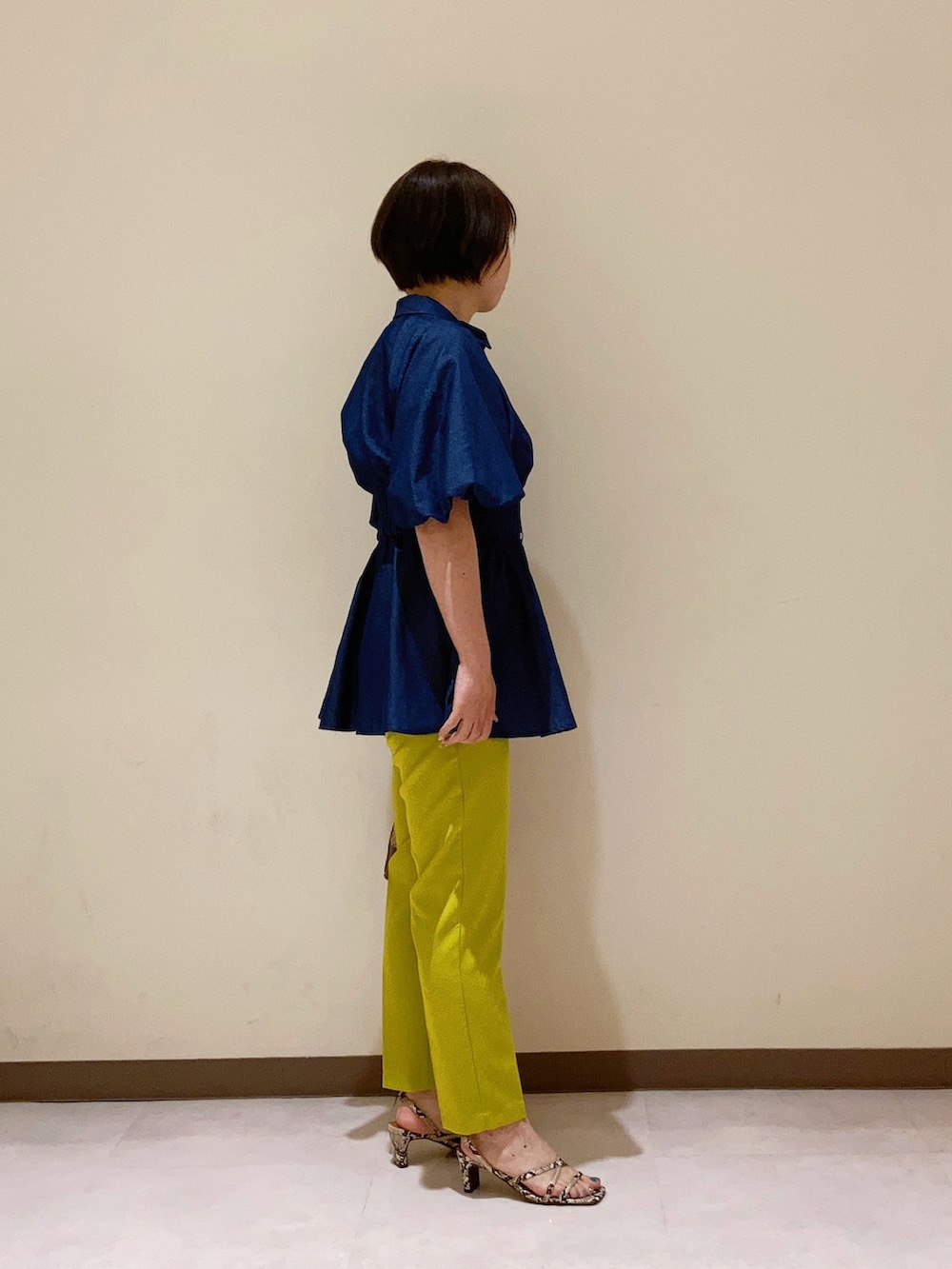 ブルー系のシャツ/ブラウス、イエロー系のパンツ、ブラウン系のハンドバッグを着用したレディースの春コーディネートの2枚目の写真