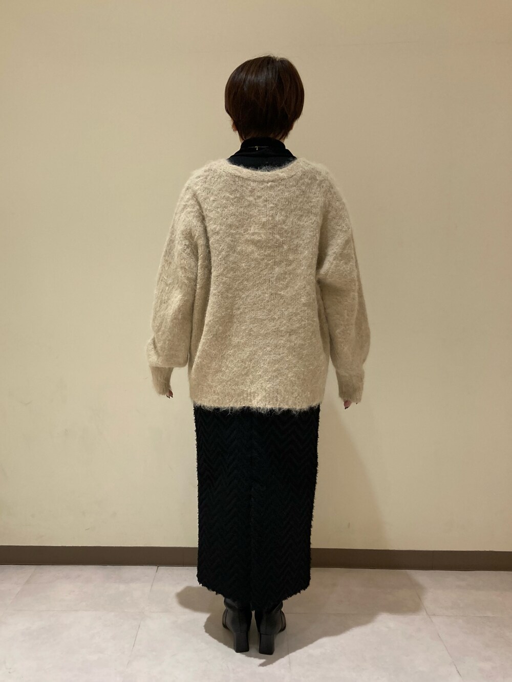 ベージュ系のカーディガン/ボレロ、ブラック系のスカート、ブラック系のブーツを着用したレディースの冬コーディネートの4枚目の写真