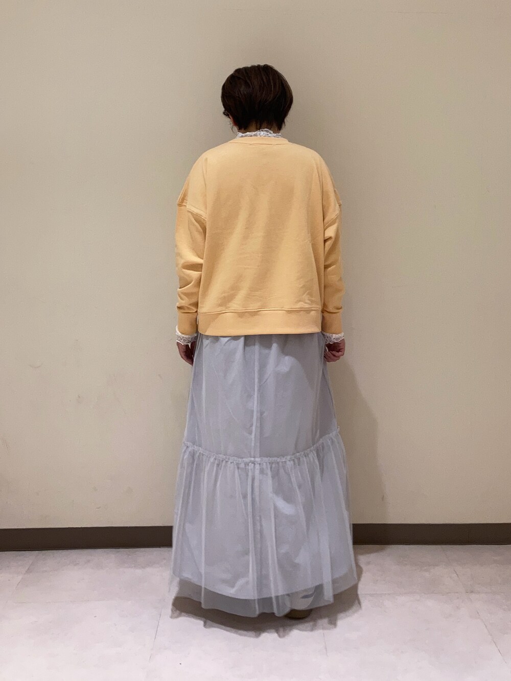 オレンジ系のTシャツ/カットソー、グレー系のスカート、ホワイト系のTシャツ/カットソーを着用したレディースの冬コーディネートの4枚目の写真