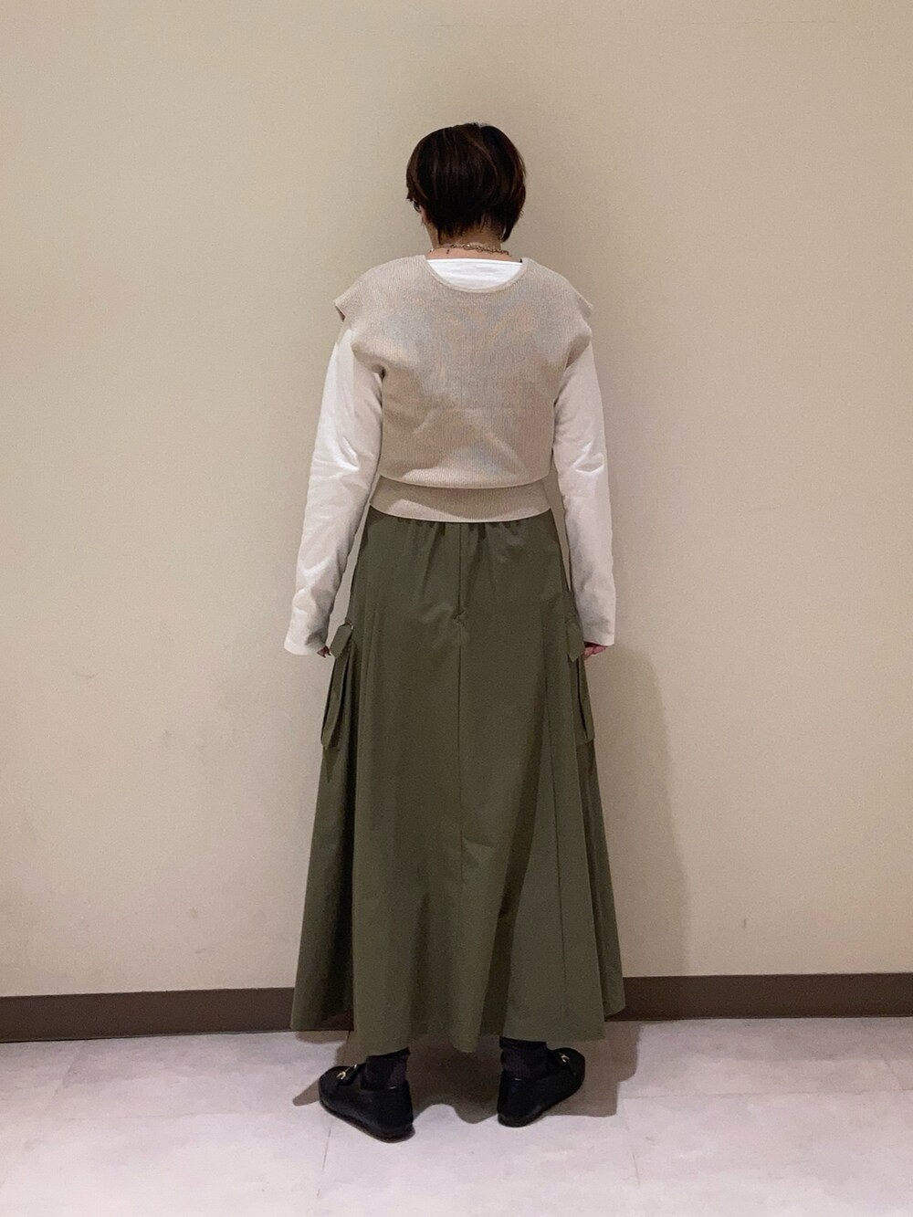 グリーン系のスカート、ベージュ系のベストを着用したレディースの冬コーディネートの4枚目の写真