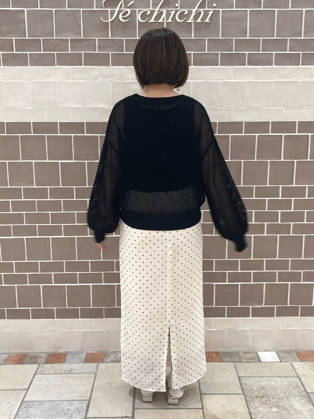 ブラック系のニット/セーター、ベージュ系のスカート、シルバー系のパンプスを着用したレディースの春コーディネートの5枚目の写真