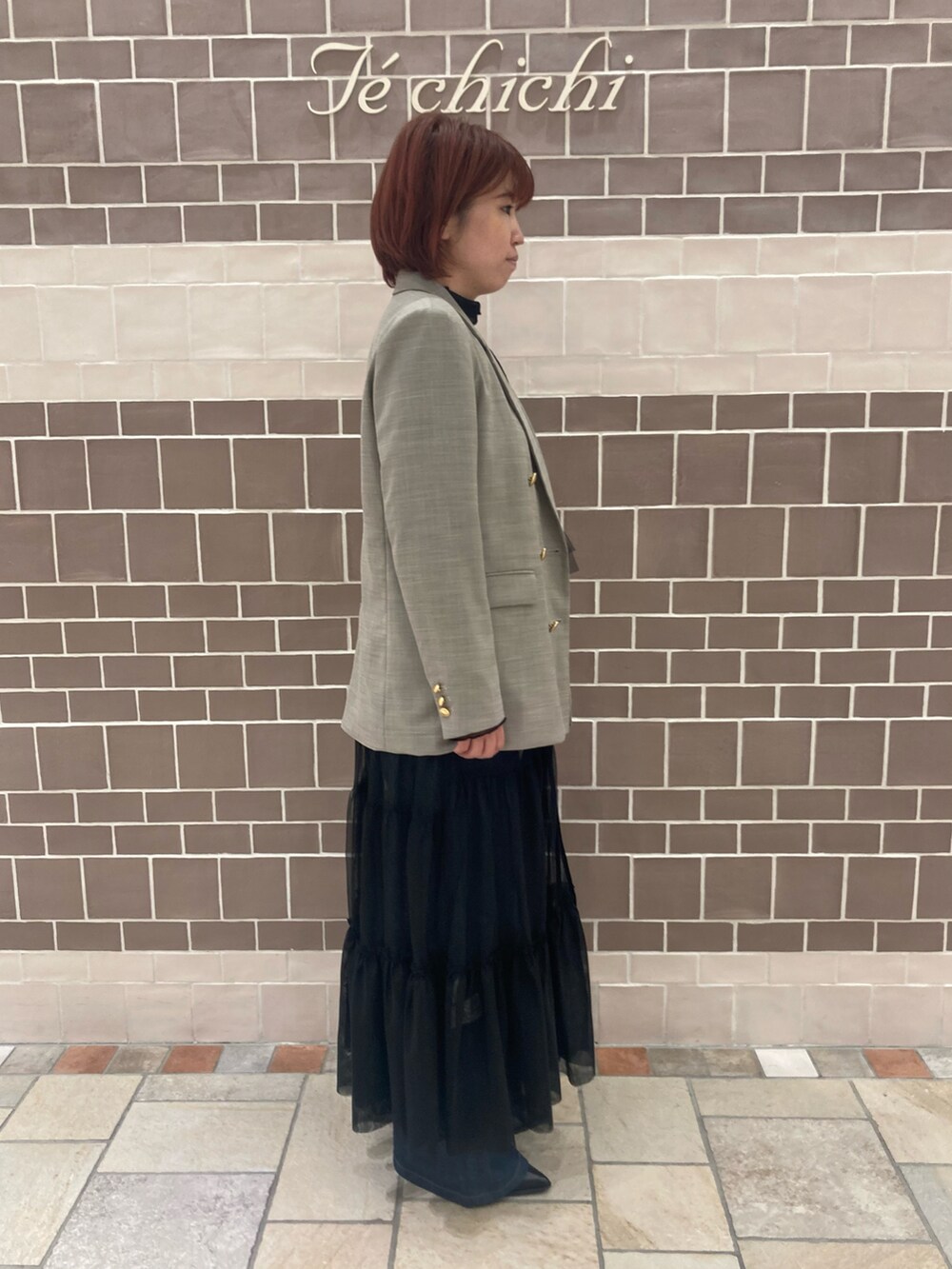 ベージュ系のノーカラージャケット、ブラック系のワンピース/ドレス、ブルー系のデニムパンツを着用したレディースの秋コーディネートの2枚目の写真